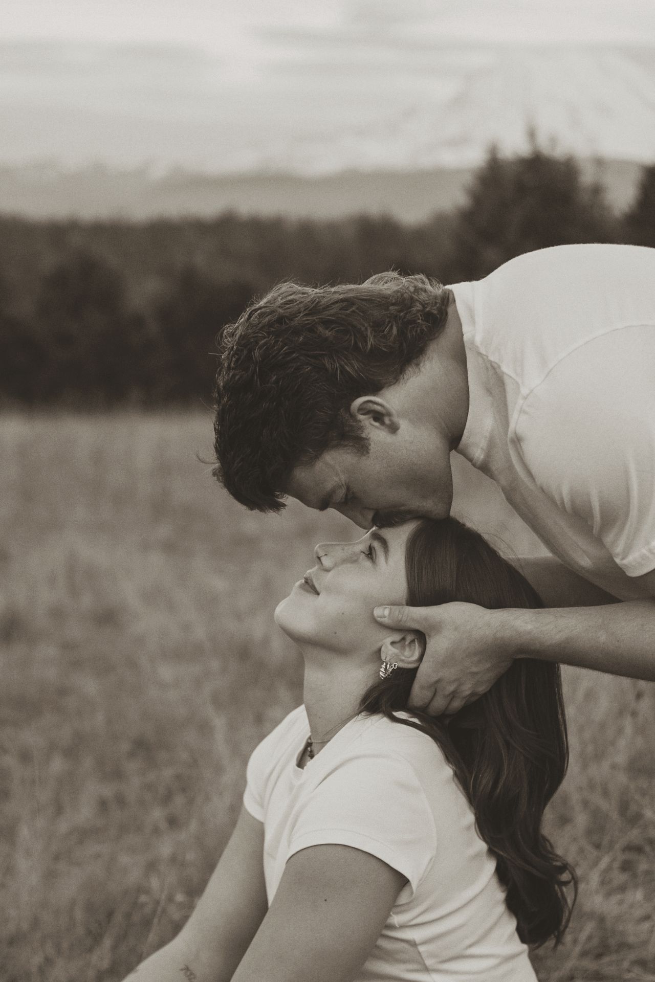 A black and white photo sequence shows a couple sharing an intimate kiss in a grassy field.