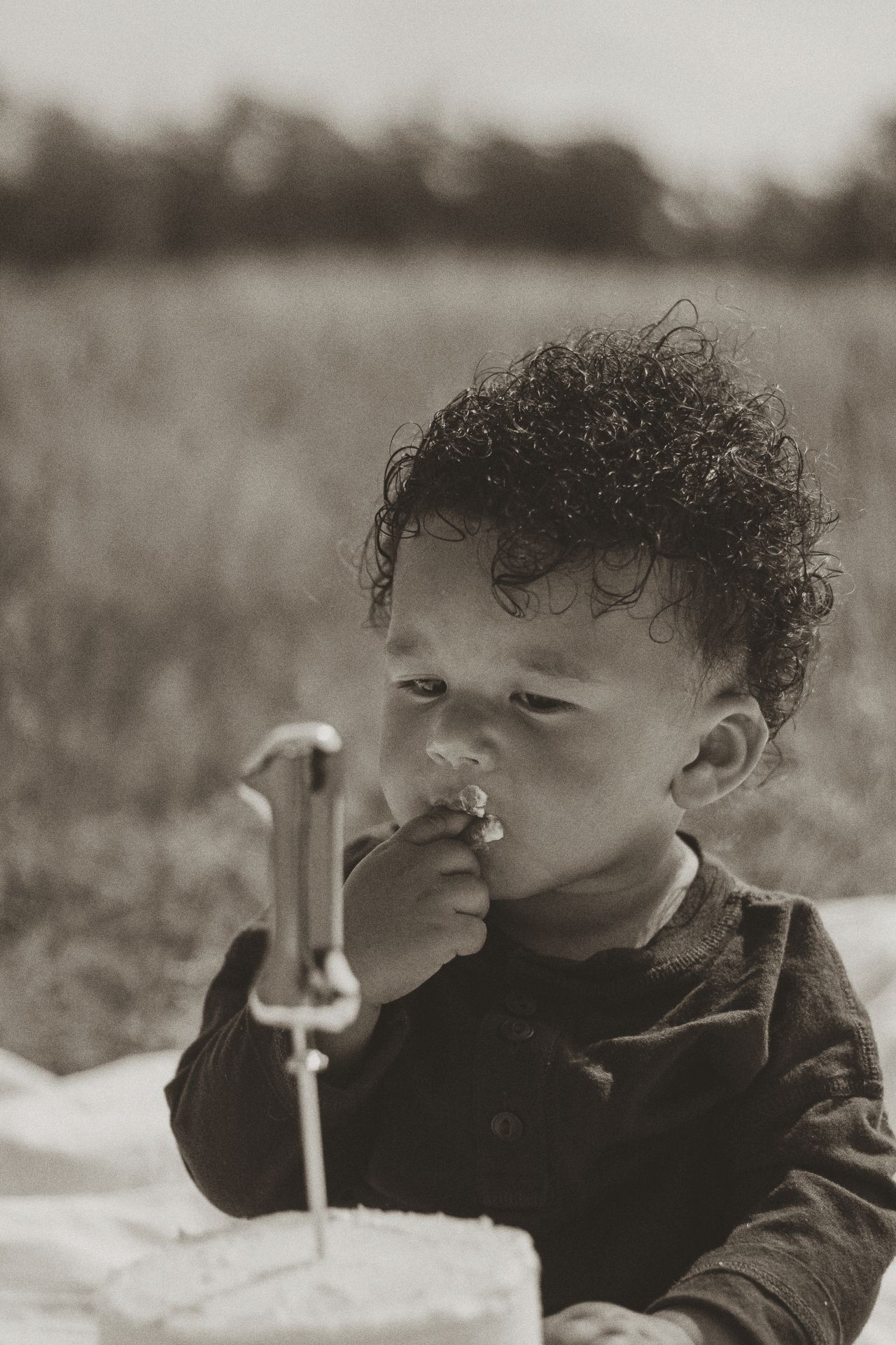 Young child with curly hair looking through a magnifying glass in black and white.