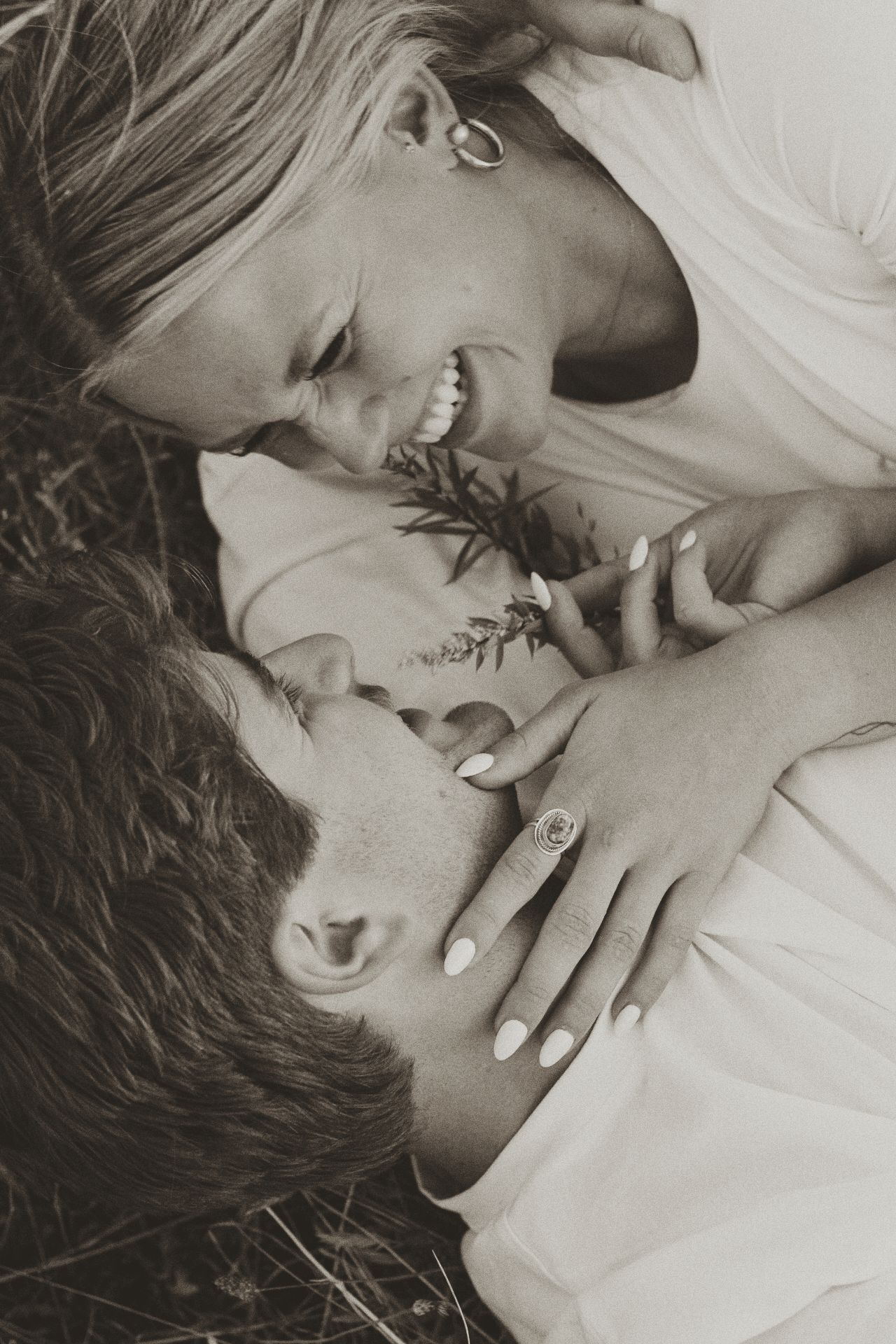 Black and white photo of a couple lying down and sharing a joyful laugh together.