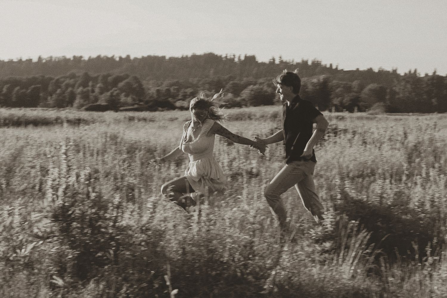 People running and playing in a wildflower meadow at sunset.