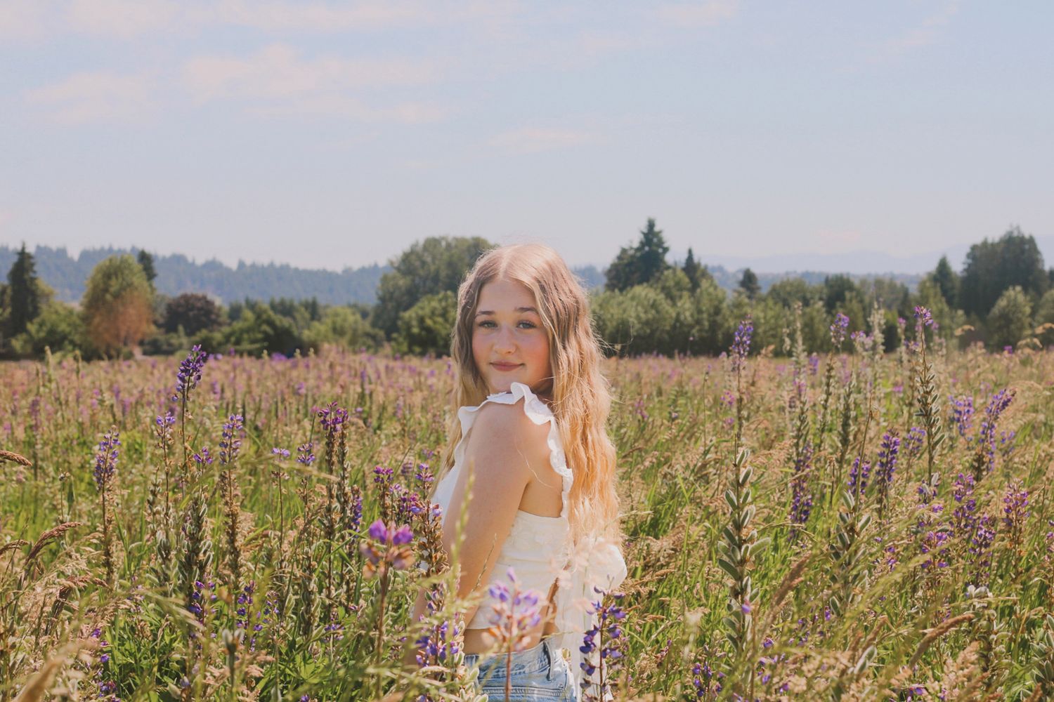 Summer portrait session in field of purple wildflowers during golden hour.
