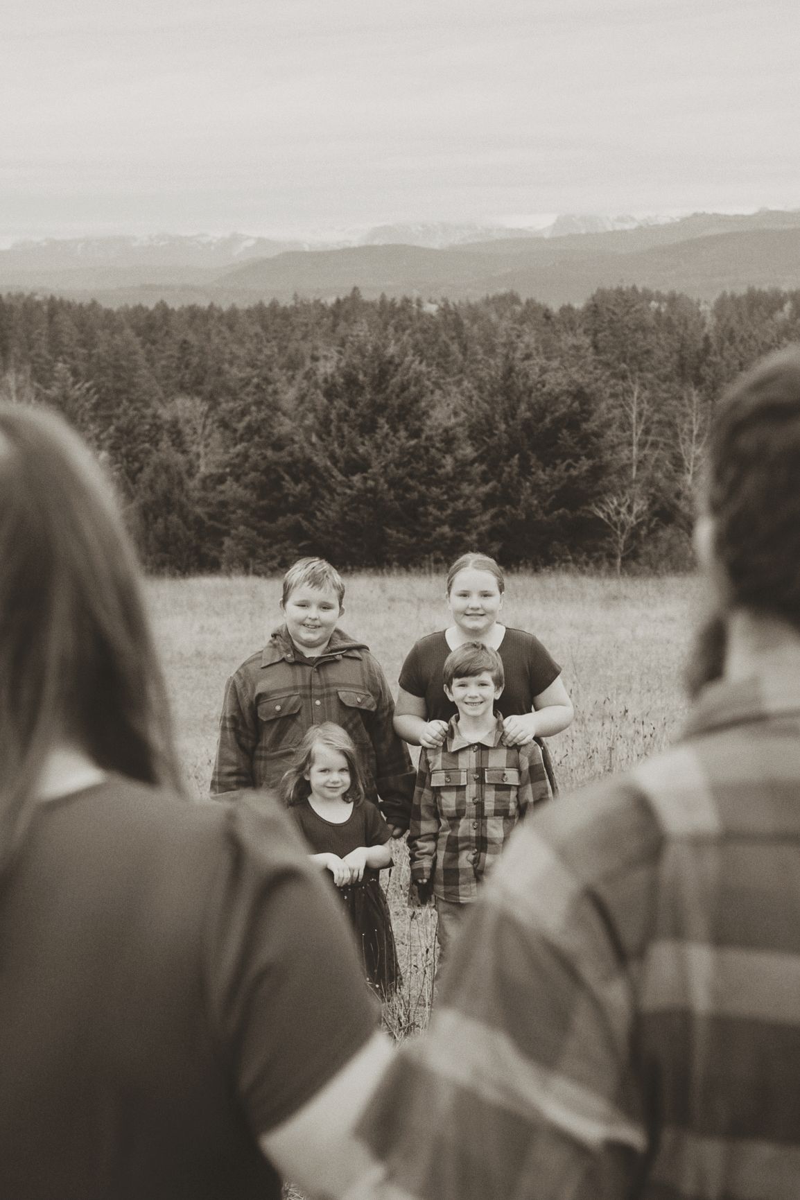 A black and white panoramic sequence showing people gathered outdoors with mountains and trees in the background.