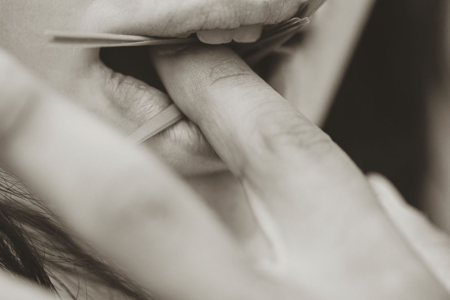 Close-up black and white photo of a person biting their finger in a thoughtful or anxious gesture.