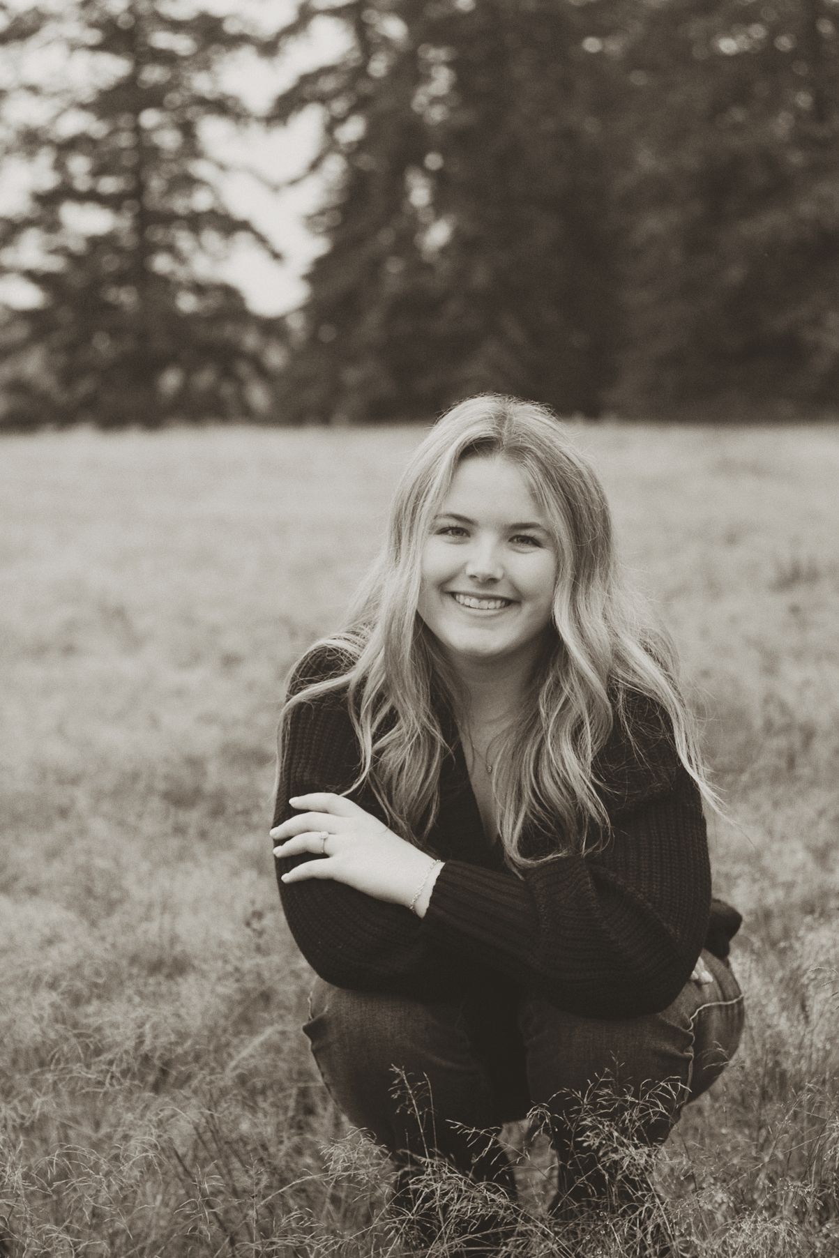 A series of black and white portraits showing someone lying in grass wearing dark clothing and smiling at the camera.