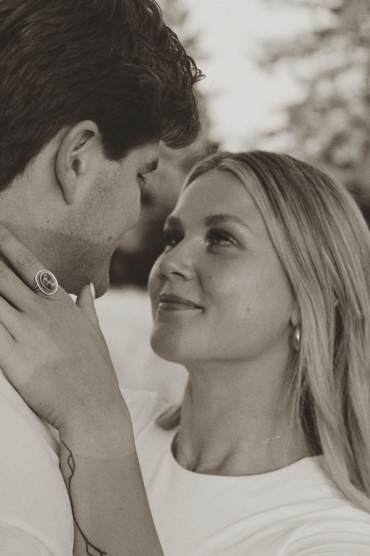 Intimate black and white portrait of a couple sharing a tender romantic moment in soft lighting.