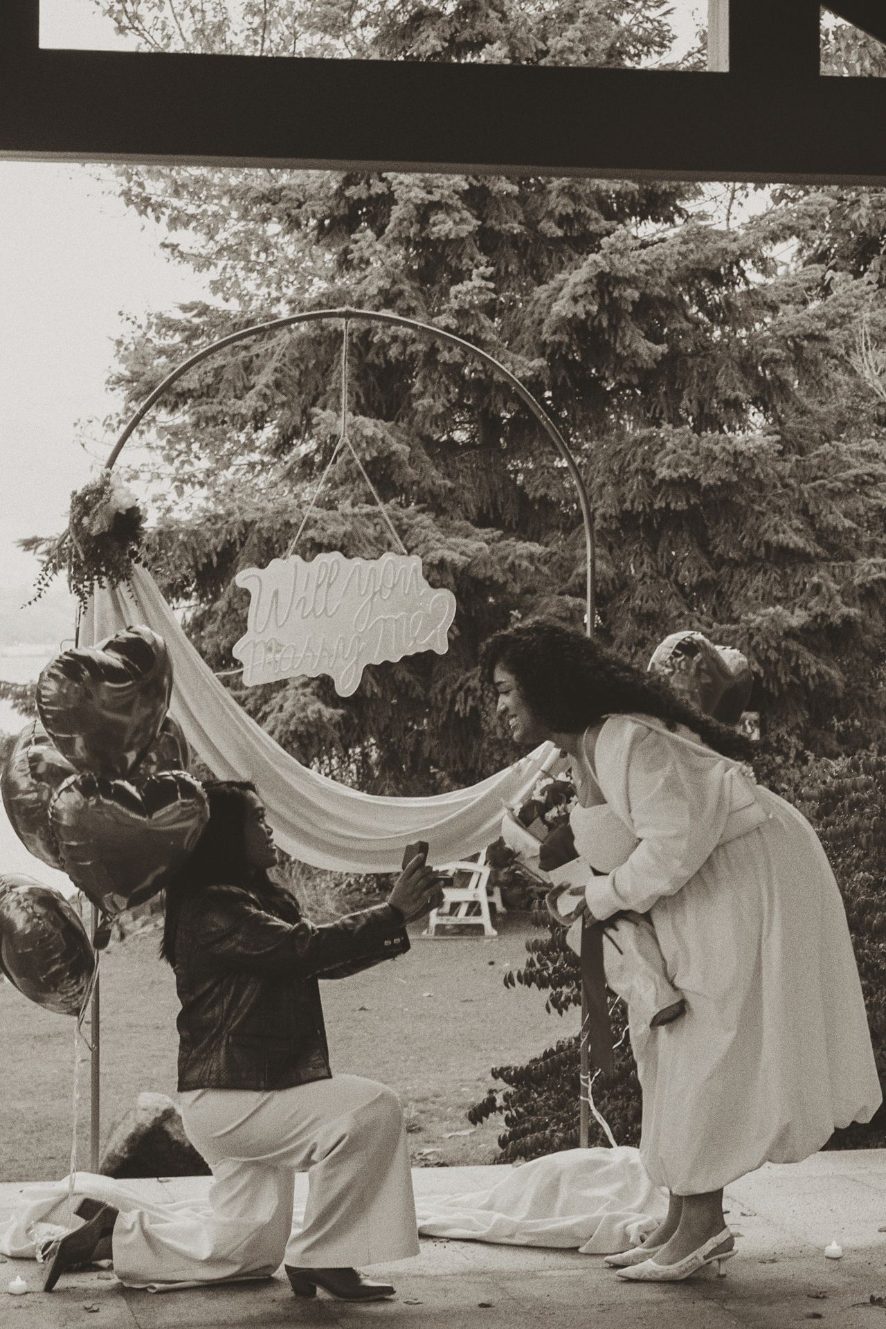 A sequence of black and white photos showing dancers performing graceful movements with flowing fabric in an outdoor setting.