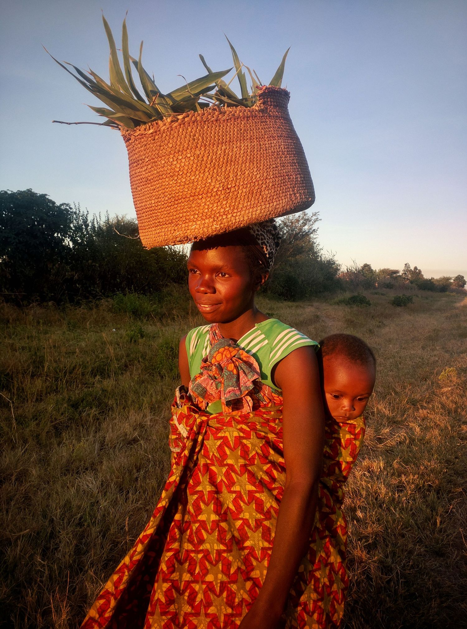Traditional African scene at sunset with woven baskets and vibrant orange clothing.