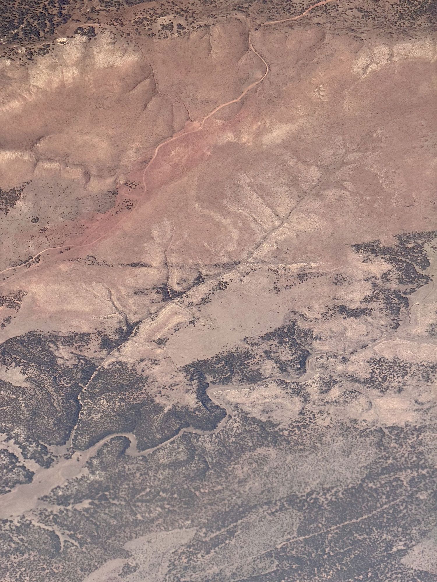 Aerial view of arid desert landscape with winding patterns and scattered vegetation.