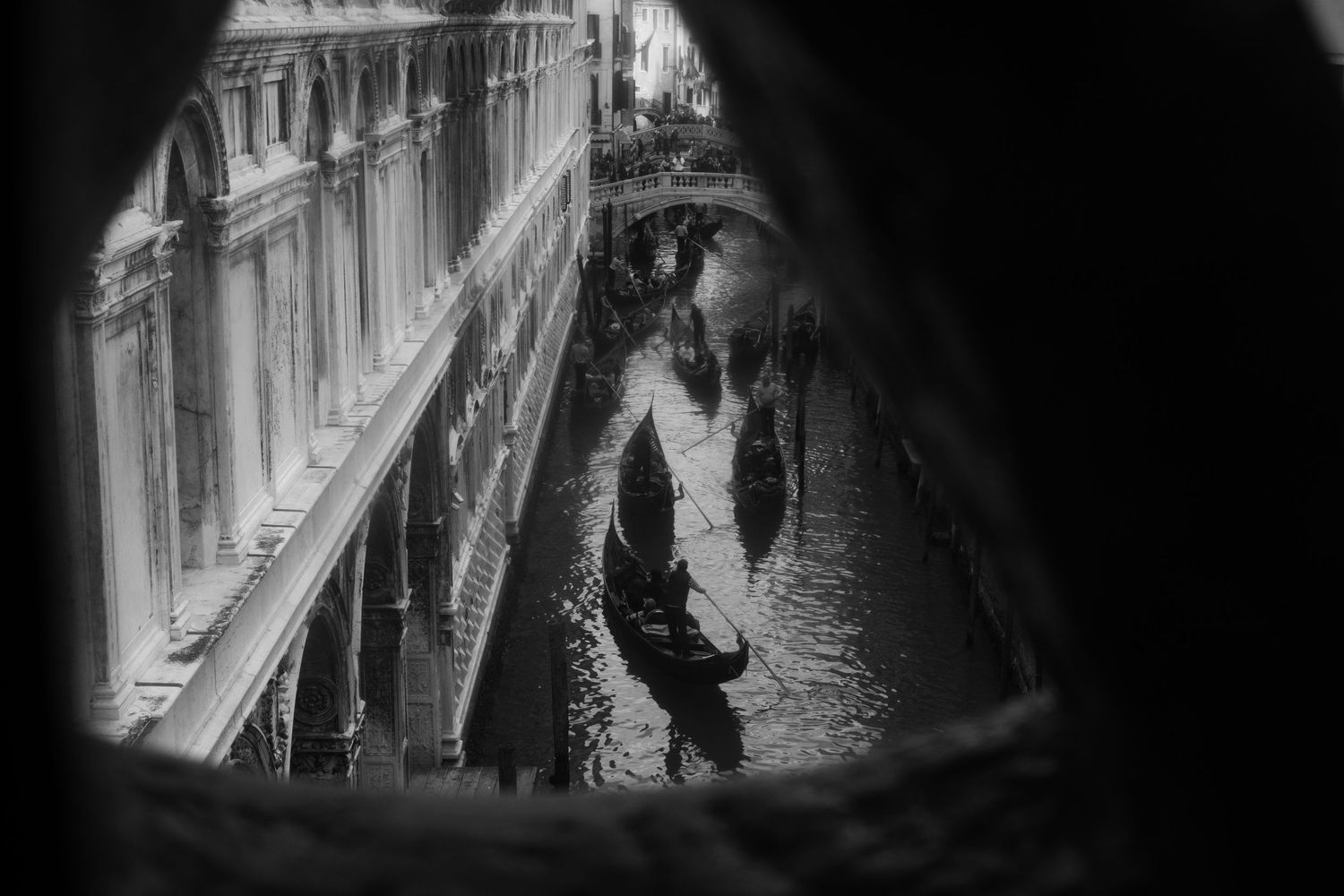 Atmospheric black and white view through window of Venice canal and architecture.