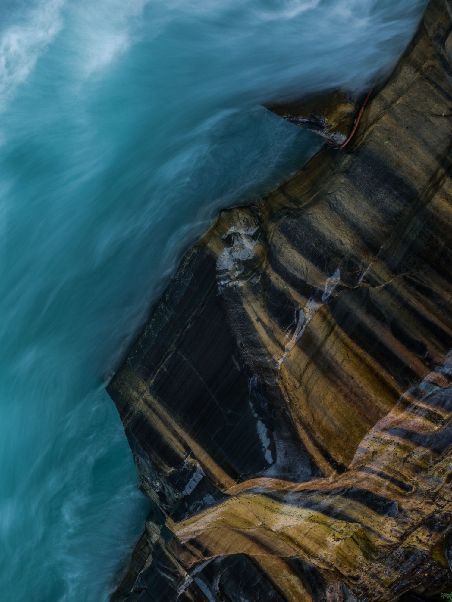 Aerial view of rugged coastal cliffs with turquoise waters and dramatic cloud formations.