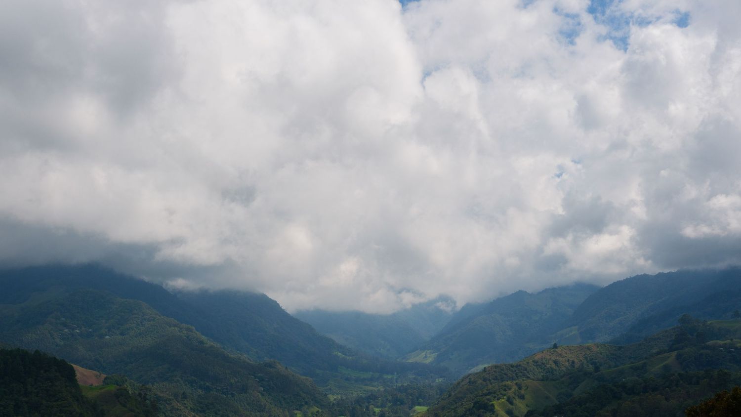 Dramatic panoramic view of misty mountains under cloudy skies stretching across the horizon.