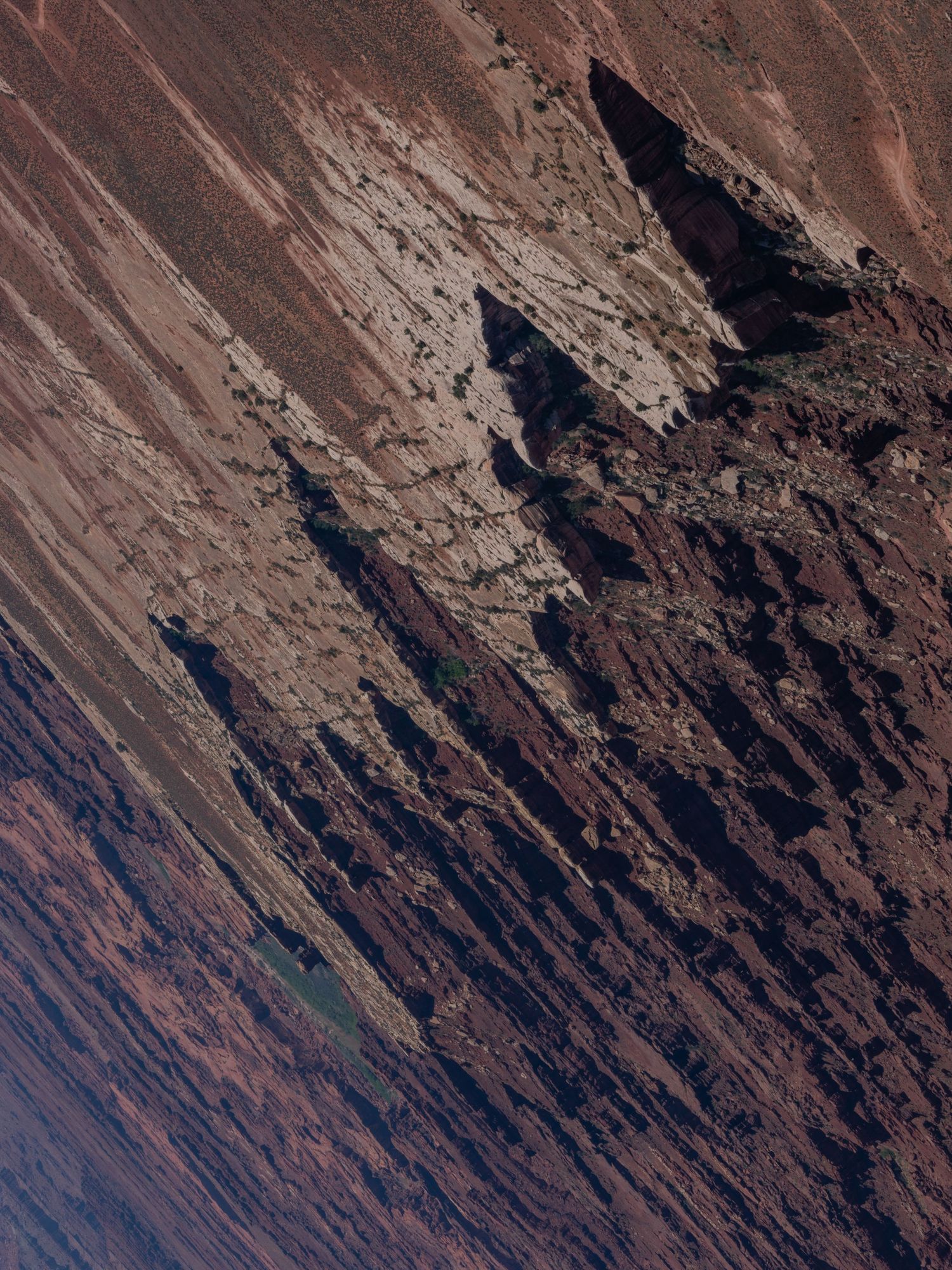 Diagonal striations in reddish-brown rock face creating natural geometric patterns.