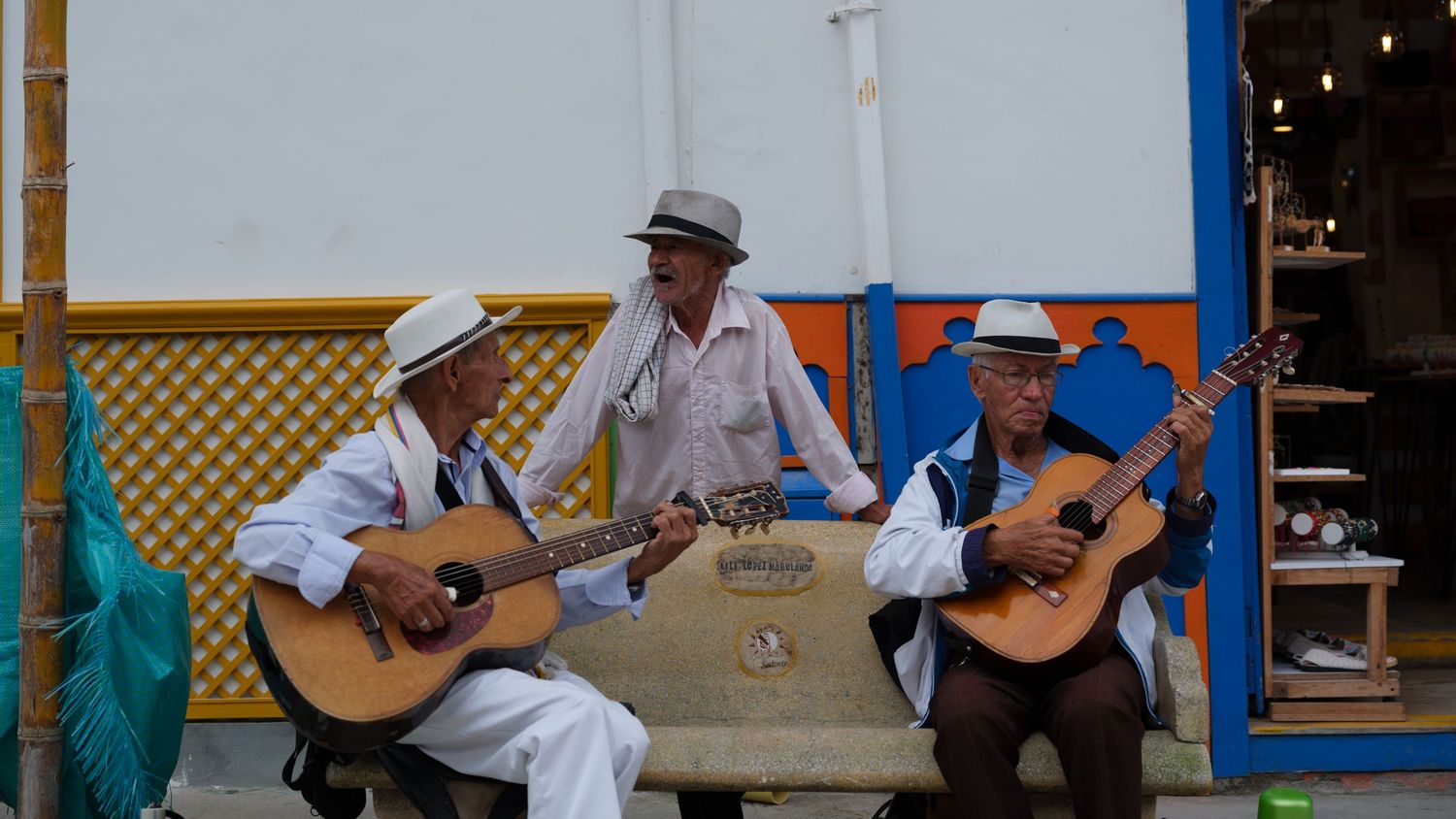 Musicians performing with traditional instruments on a colorful porch.