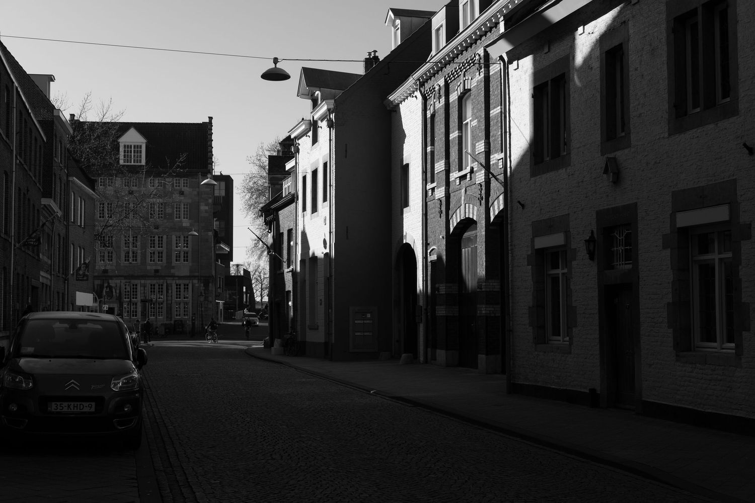 Moody black and white street scene with historic buildings and parked cars.