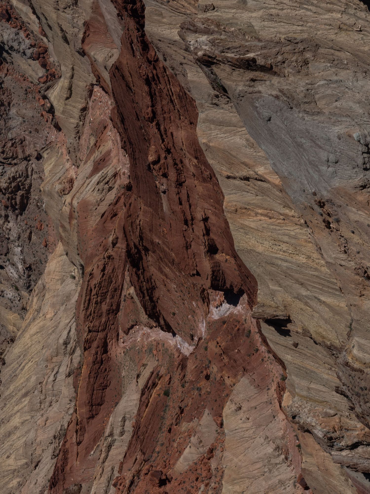 Layered red rock formations in a desert canyon with dramatic angular patterns.