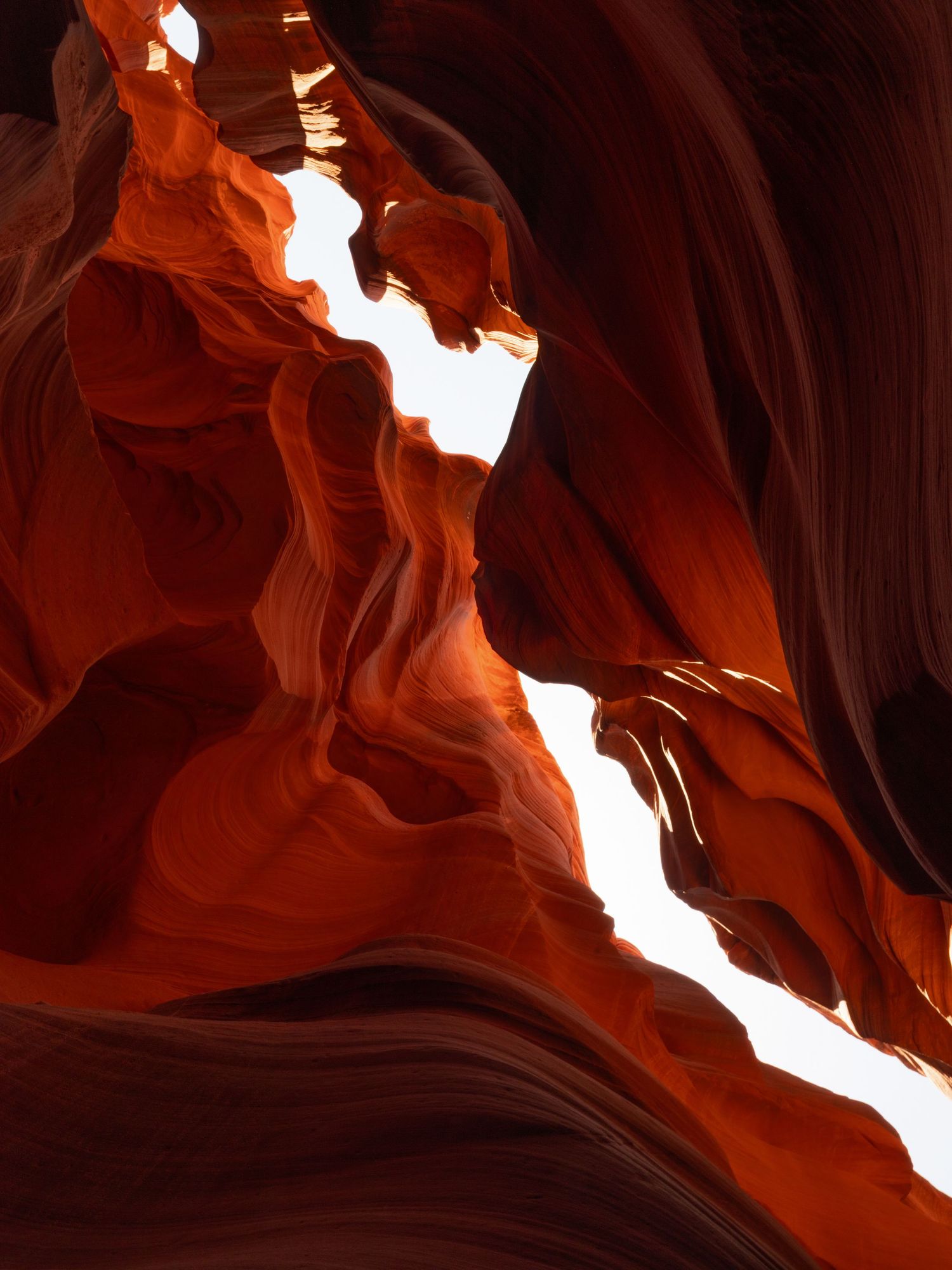 Dramatic light beams streaming through slot canyon with glowing orange walls.