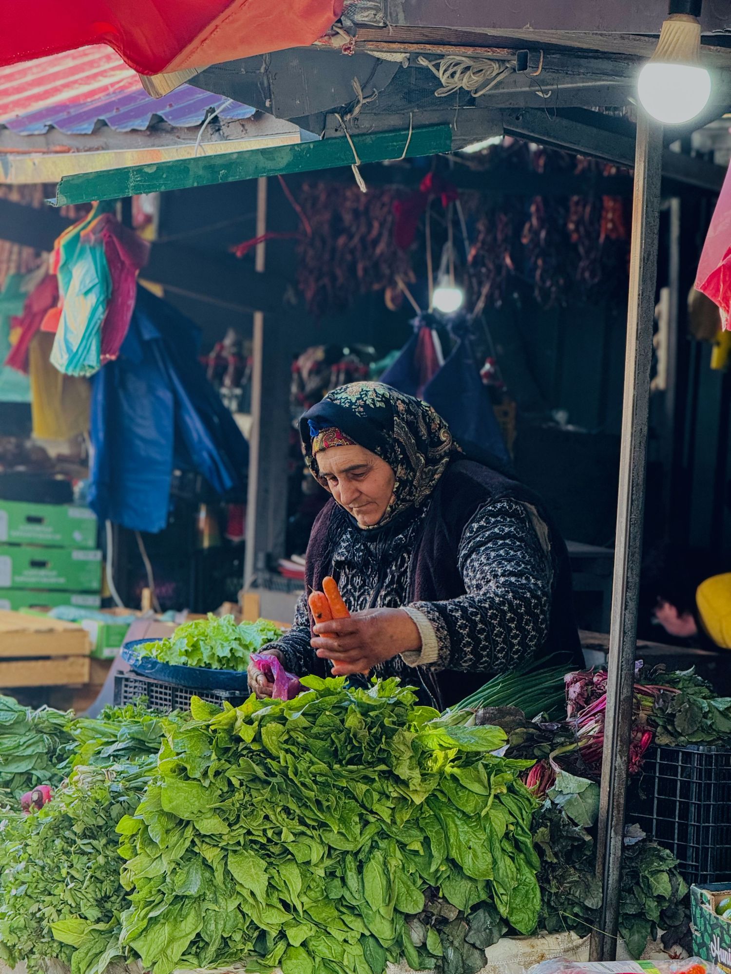 Fresh green herbs and produce displayed at outdoor market stall.