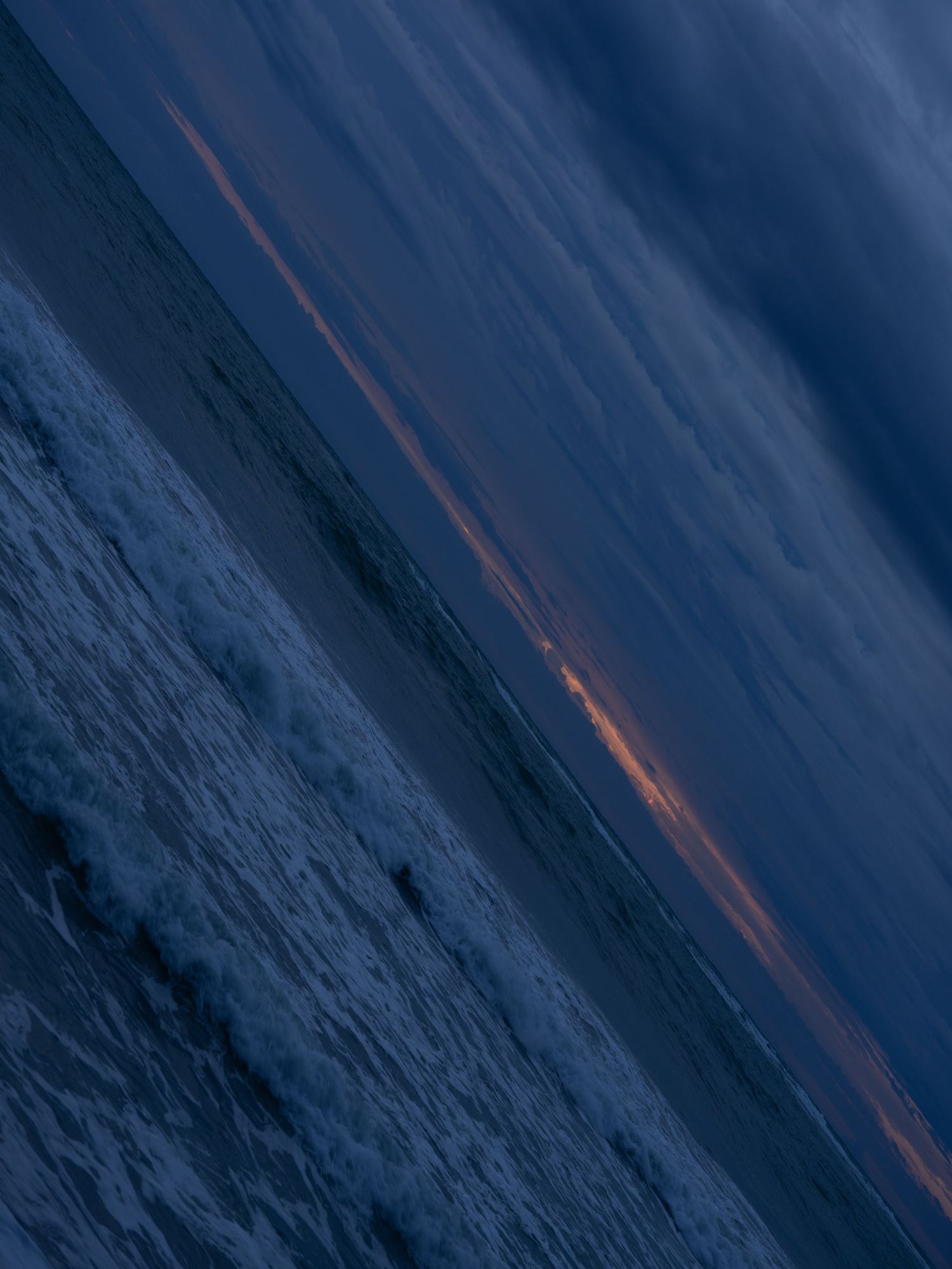 Deep blue ocean waves with orange sunlight streaks reflecting across the surface.
