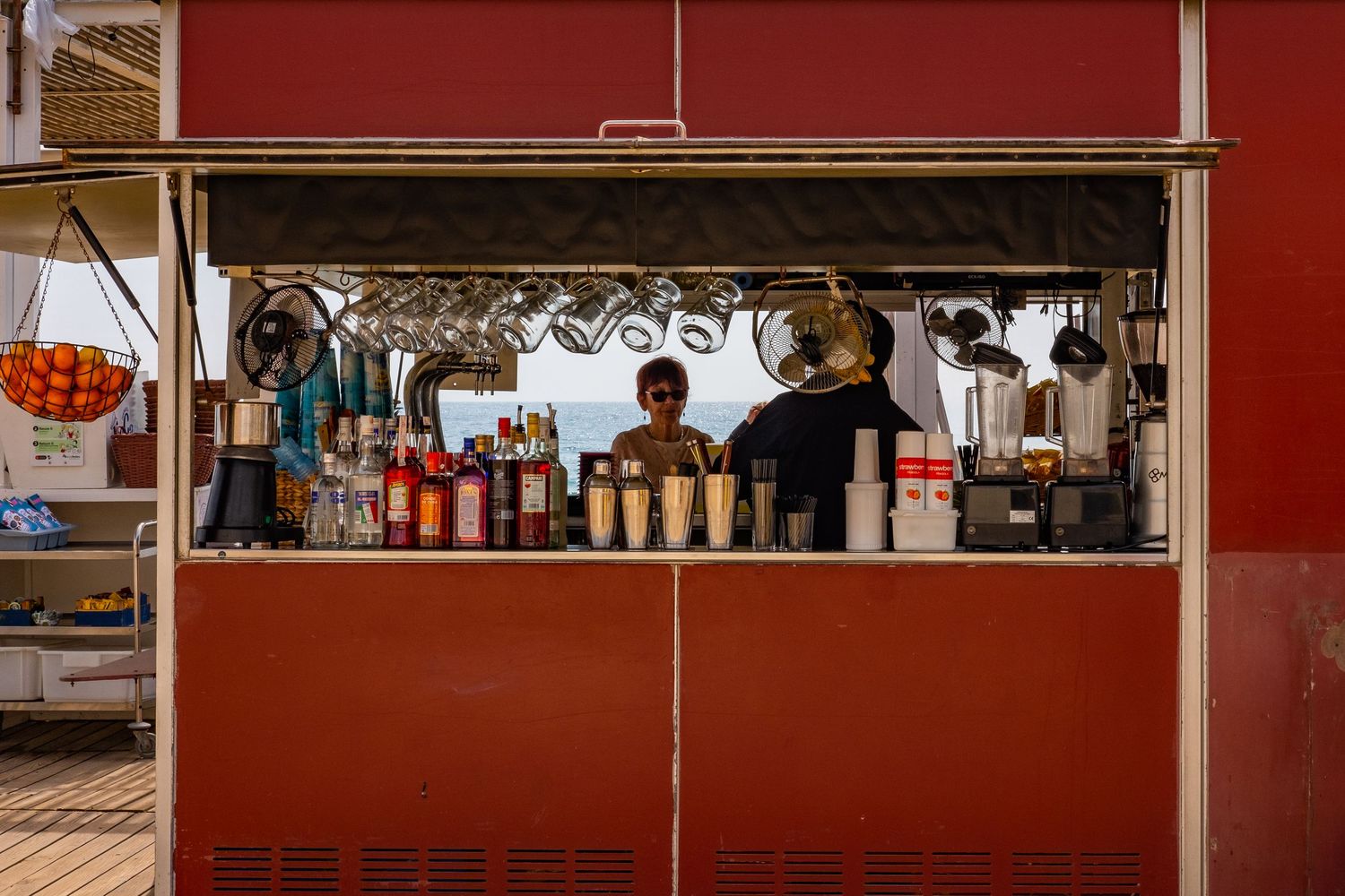 Red-walled food stall or market counter with hanging utensils and service windows.