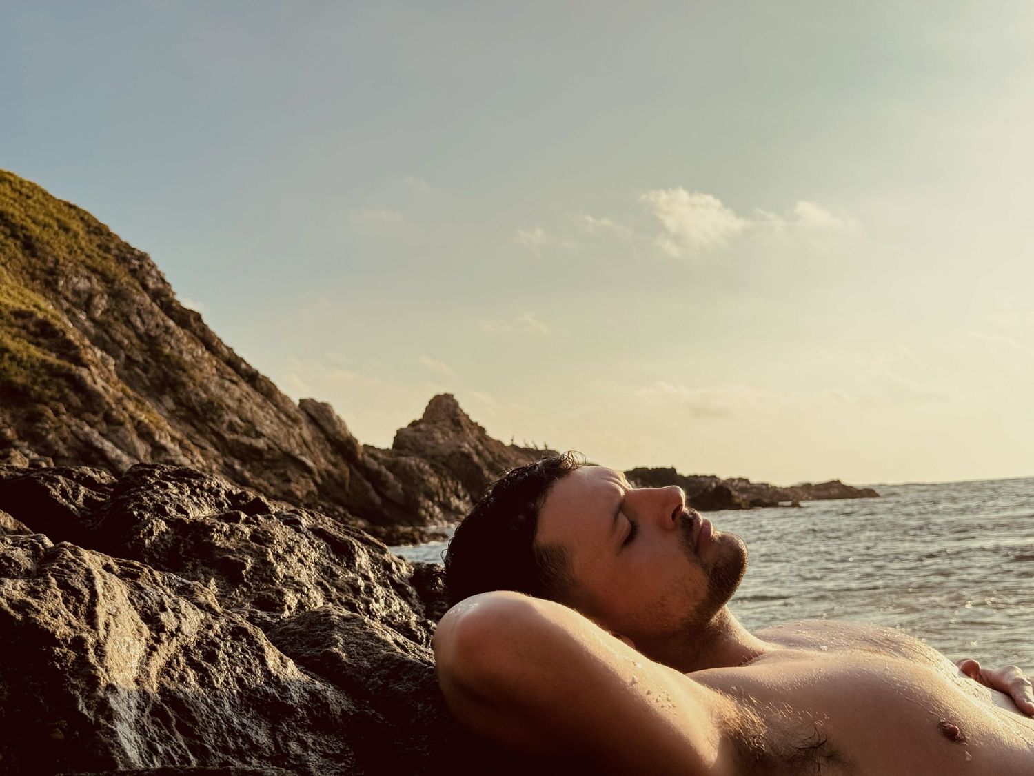 Artistic seaside portrait against rocky coastal cliffs during sunset.