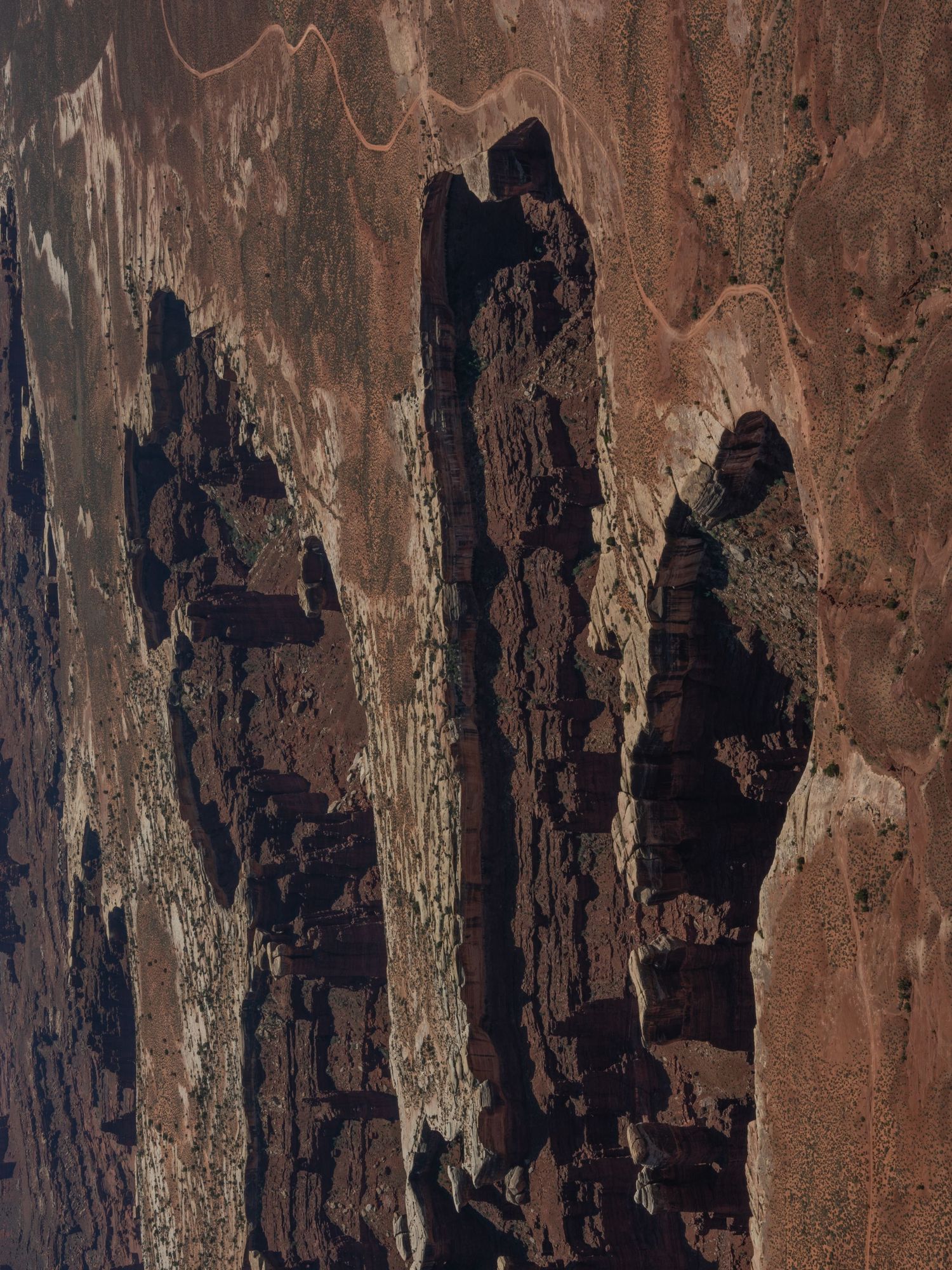 Close-up view of weathered red rock formations with dark striations and patterns in the stone.