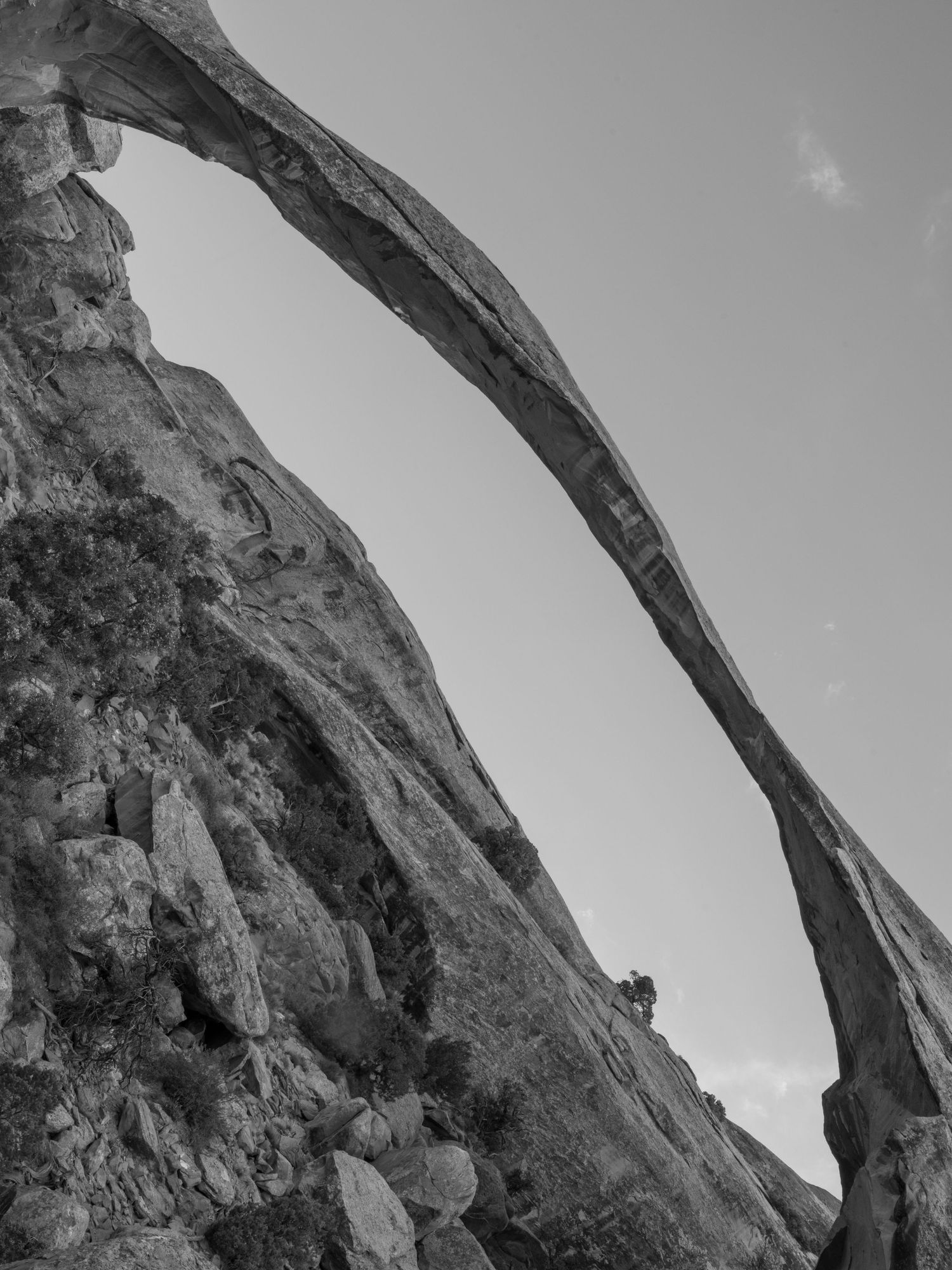 Natural stone arch formation against a cloudy sky in a desert landscape.