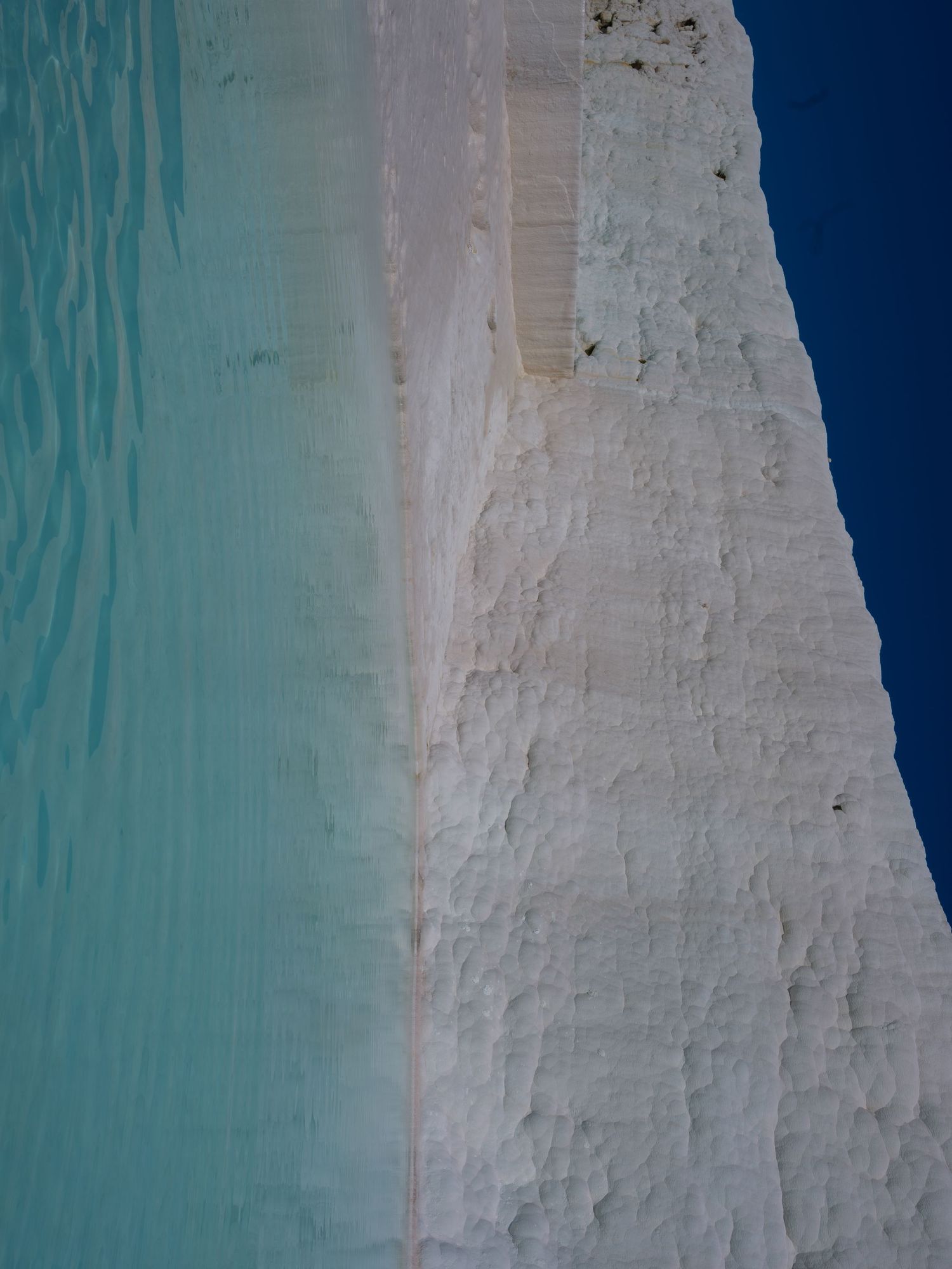 Close-up view of a white limestone cliff face against turquoise water.