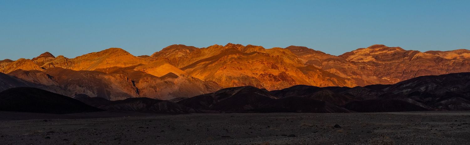 Red rock mountains glow during golden hour in desert landscape.