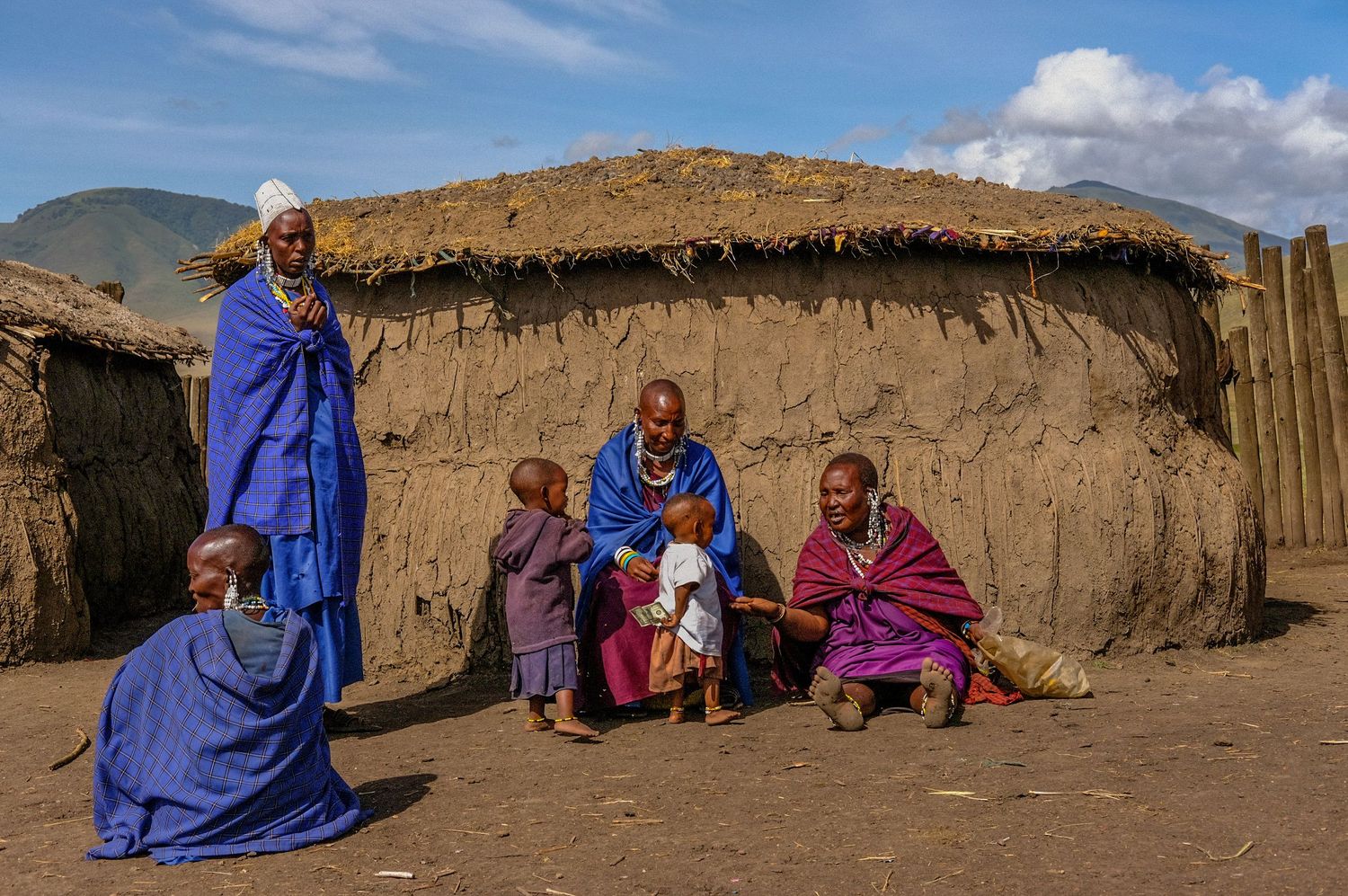 Traditional mud hut dwelling with people in colorful robes gathered outside.