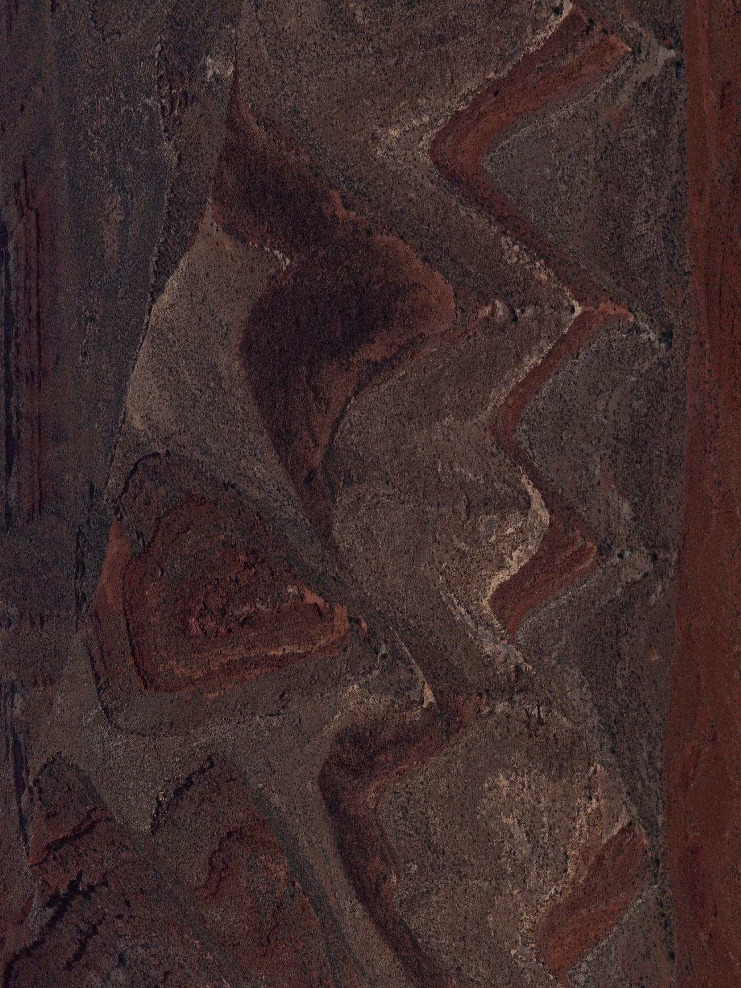 Abstract pattern of brown and rust colored rock formations with curved lines.