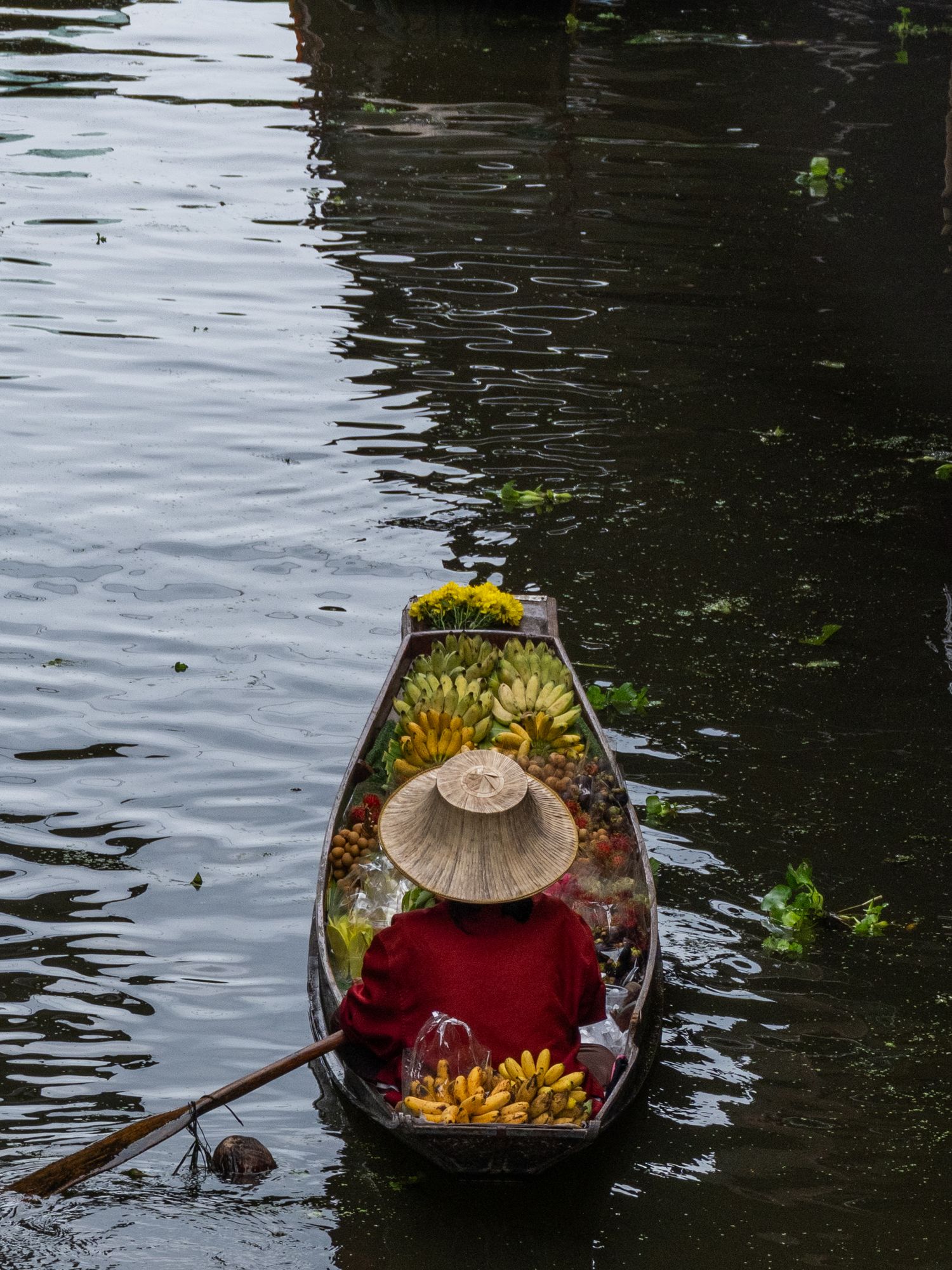 Traditional wooden boat loaded with fresh produce floating on dark water.