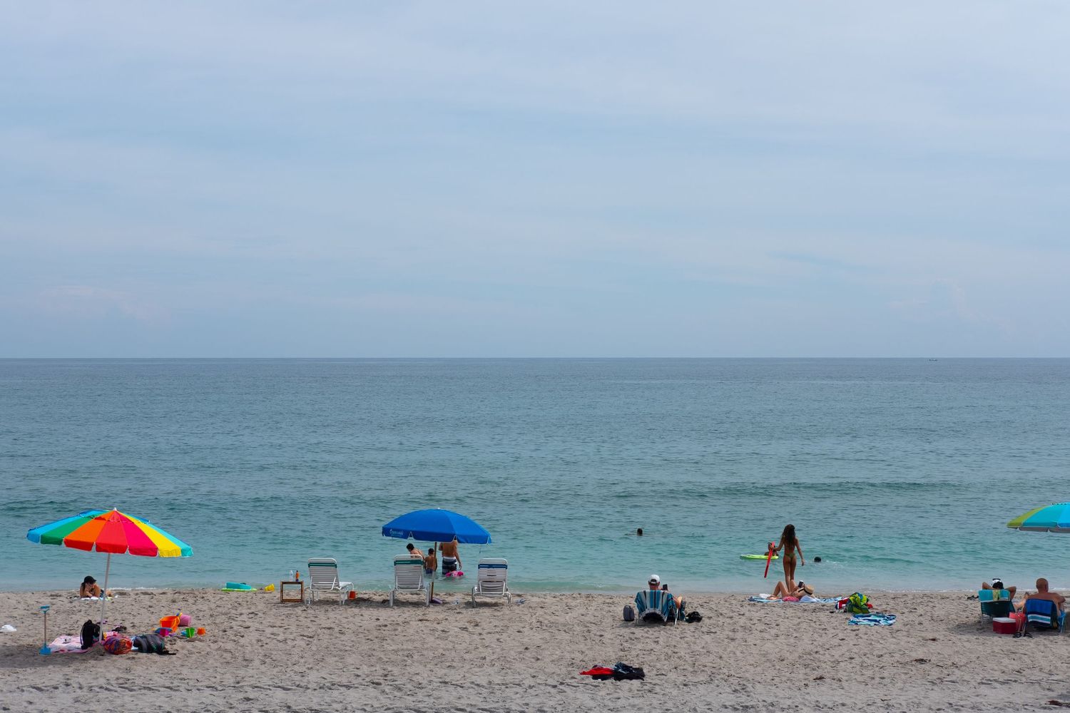 Colorful beach umbrellas dot the sandy shoreline on a sunny summer day.