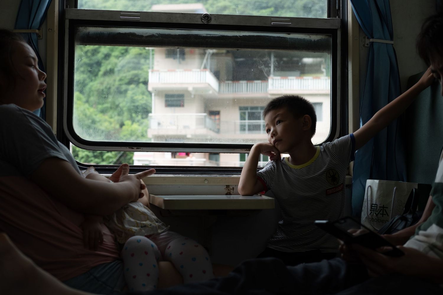 Train passengers gazing out the window at mountain scenery during their journey.