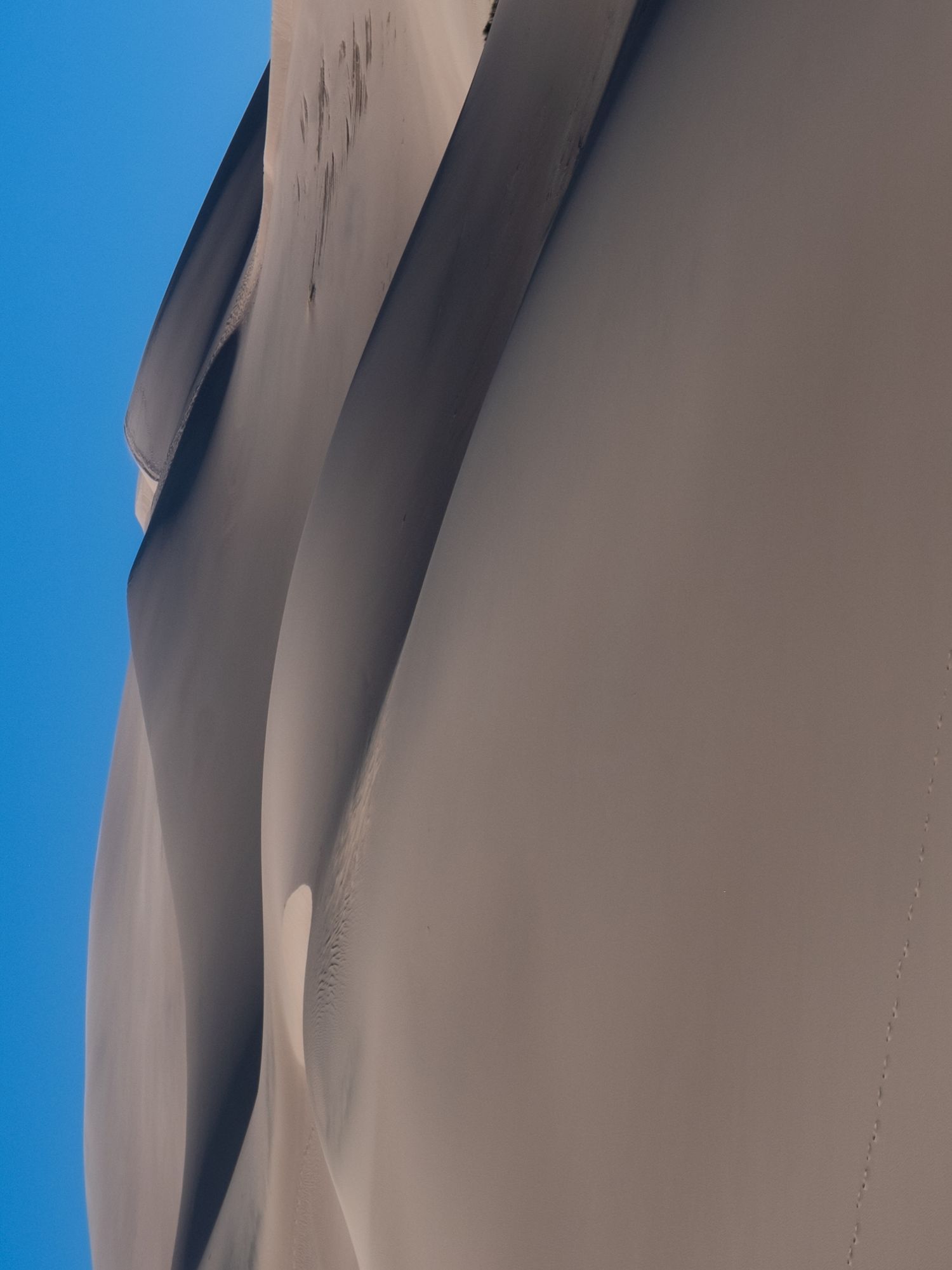 Abstract architectural detail of curved white walls against bright blue sky.