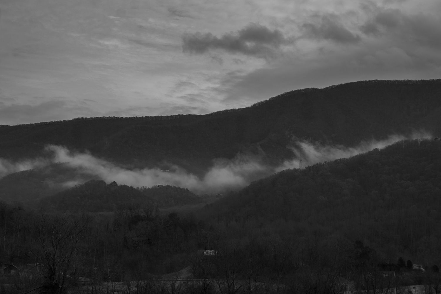 Misty mountains under dramatic cloudy skies at dusk.
