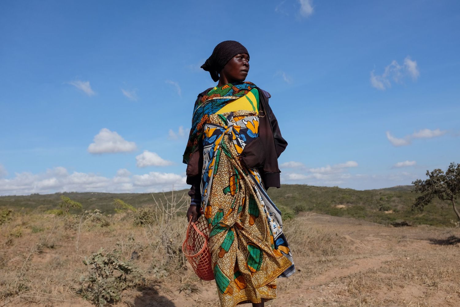 Silhouettes of people walking against a bright sky in an African landscape.