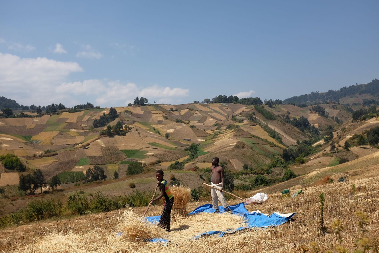 Rolling hills and mountains stretch across a rural landscape under blue skies.