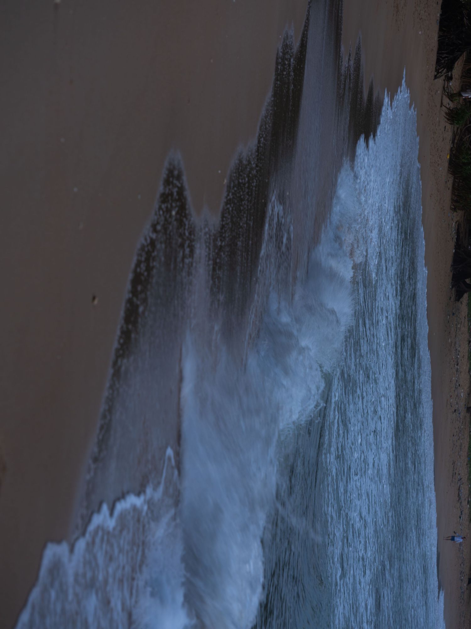 Dramatic blue ice formations cascading down a dark rocky cliff face.