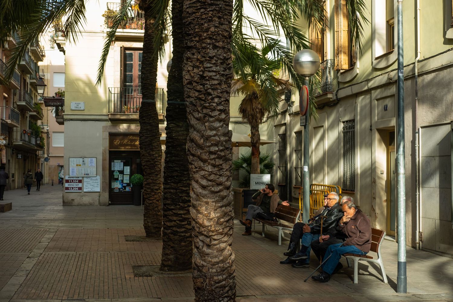 Palm tree lined street with modern buildings and pedestrians in an urban setting.