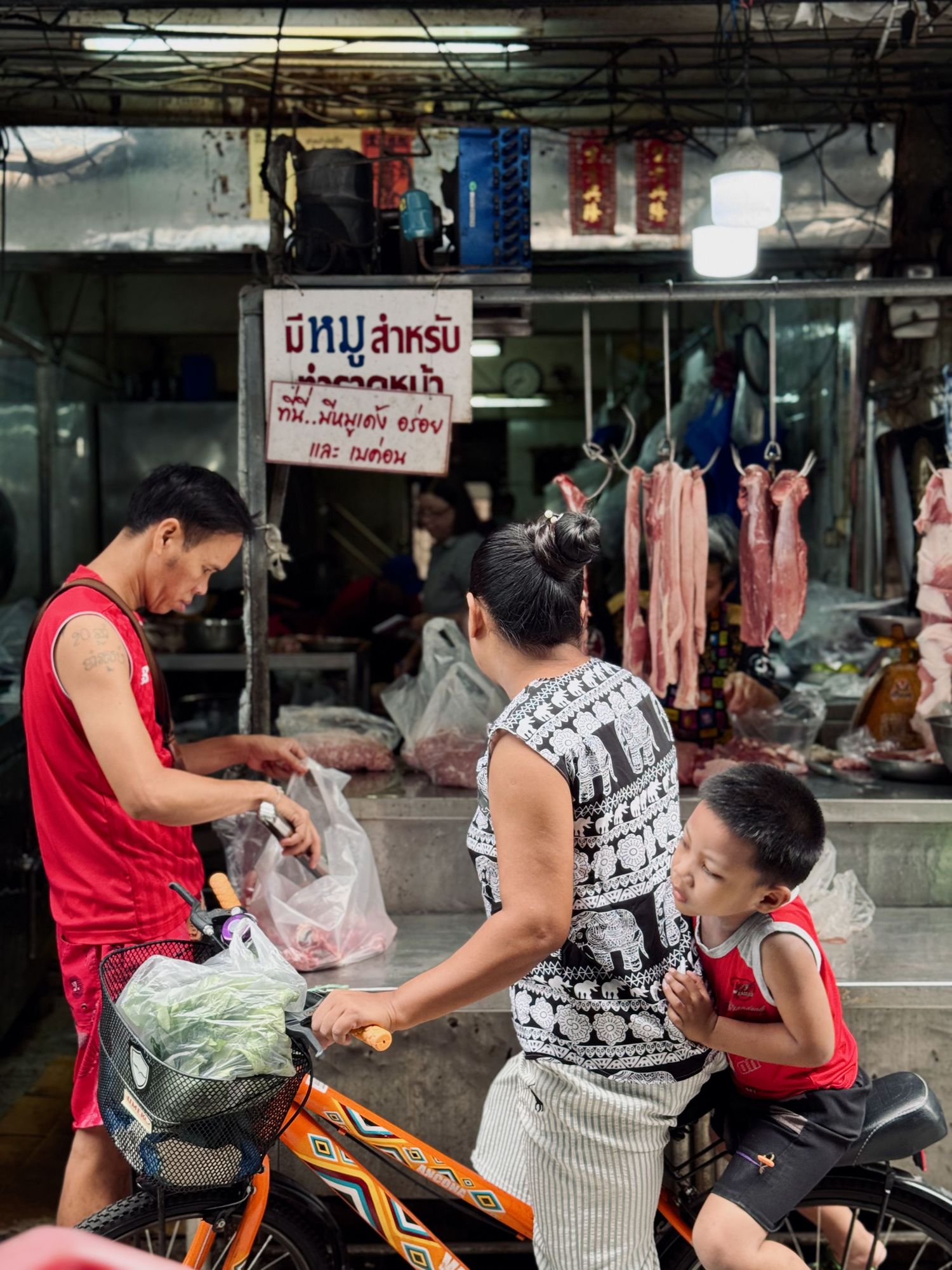 Interior of busy Asian meat market with vendors and customers.