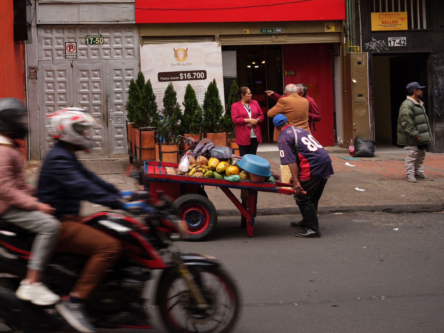 Blurred urban street scene with motorcycles and pedestrians in motion.