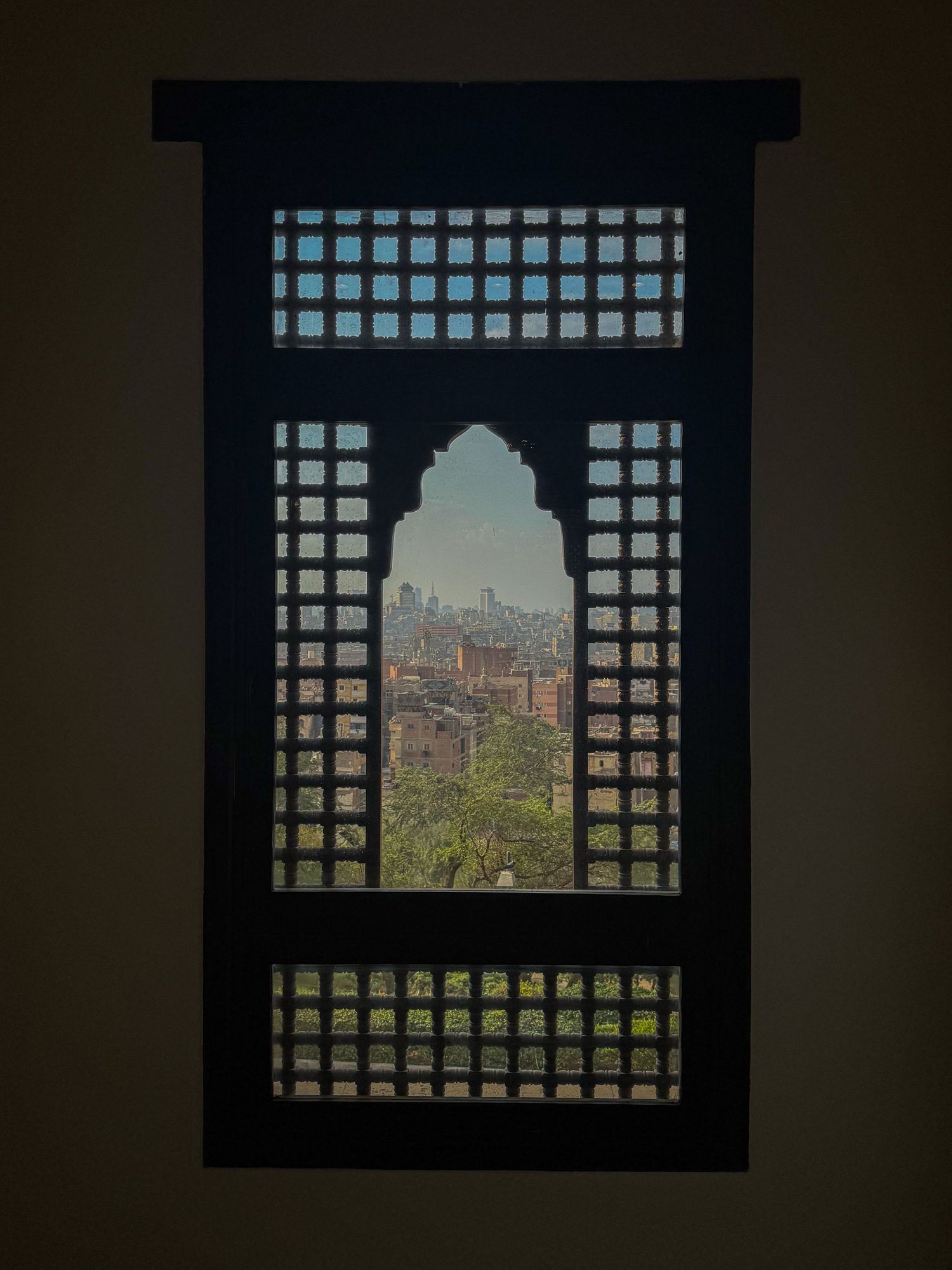 View of city skyline through traditional Islamic latticed window screen.