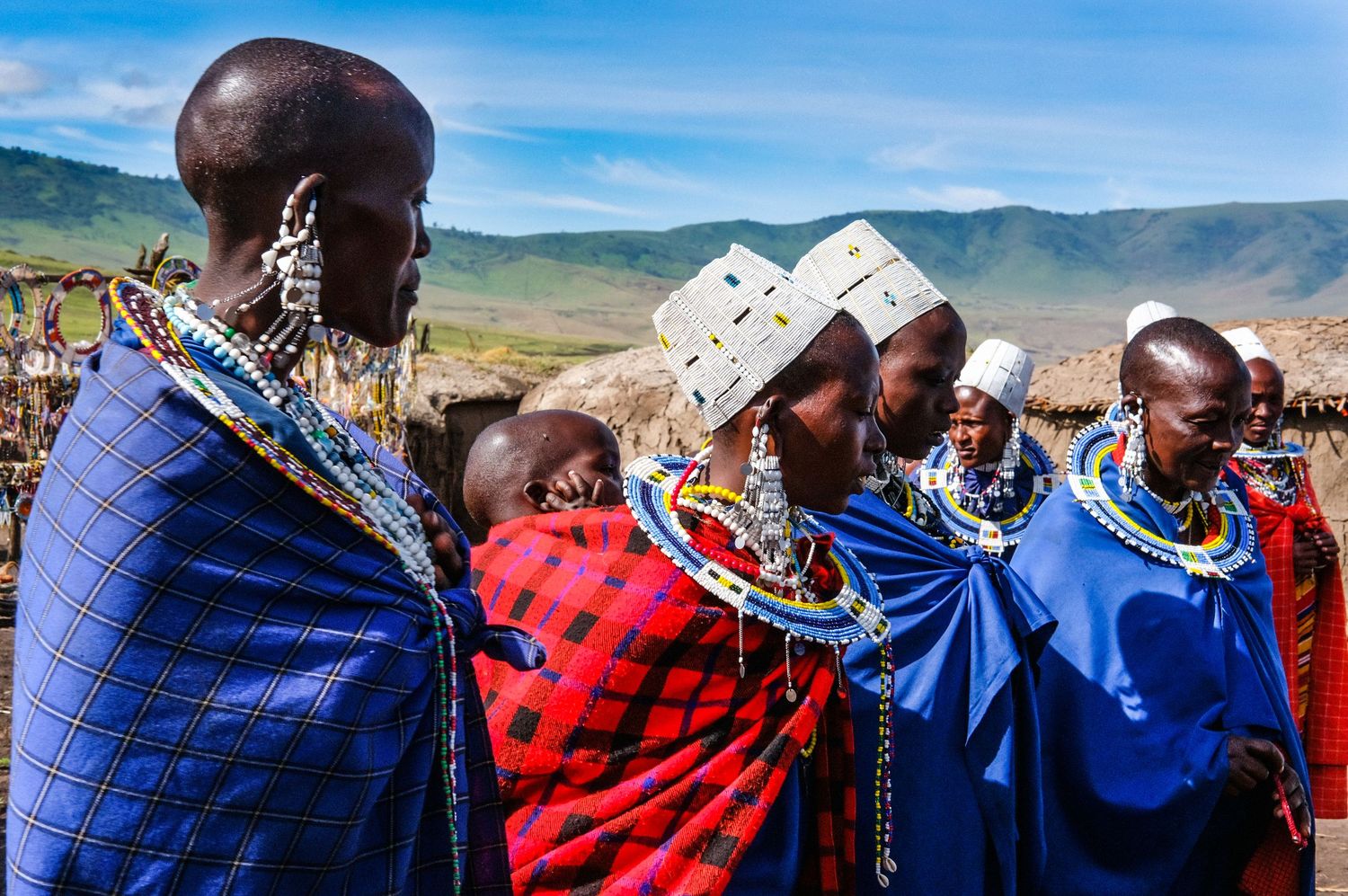 A panoramic collage of traditional Maasai tribespeople in colorful red and blue garments against a mountainous landscape.