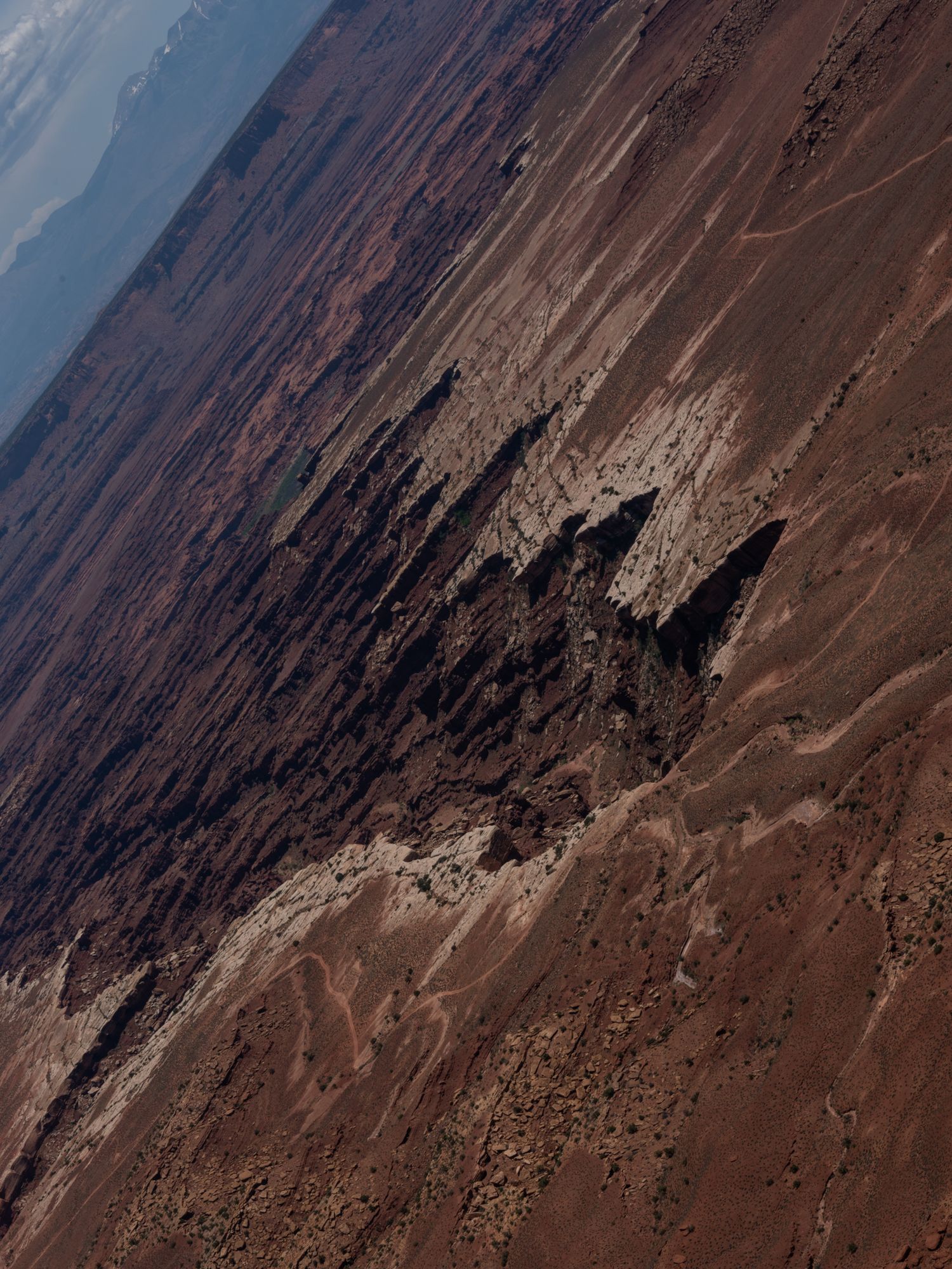 Aerial view of dramatic desert canyons and rock formations under a blue sky.