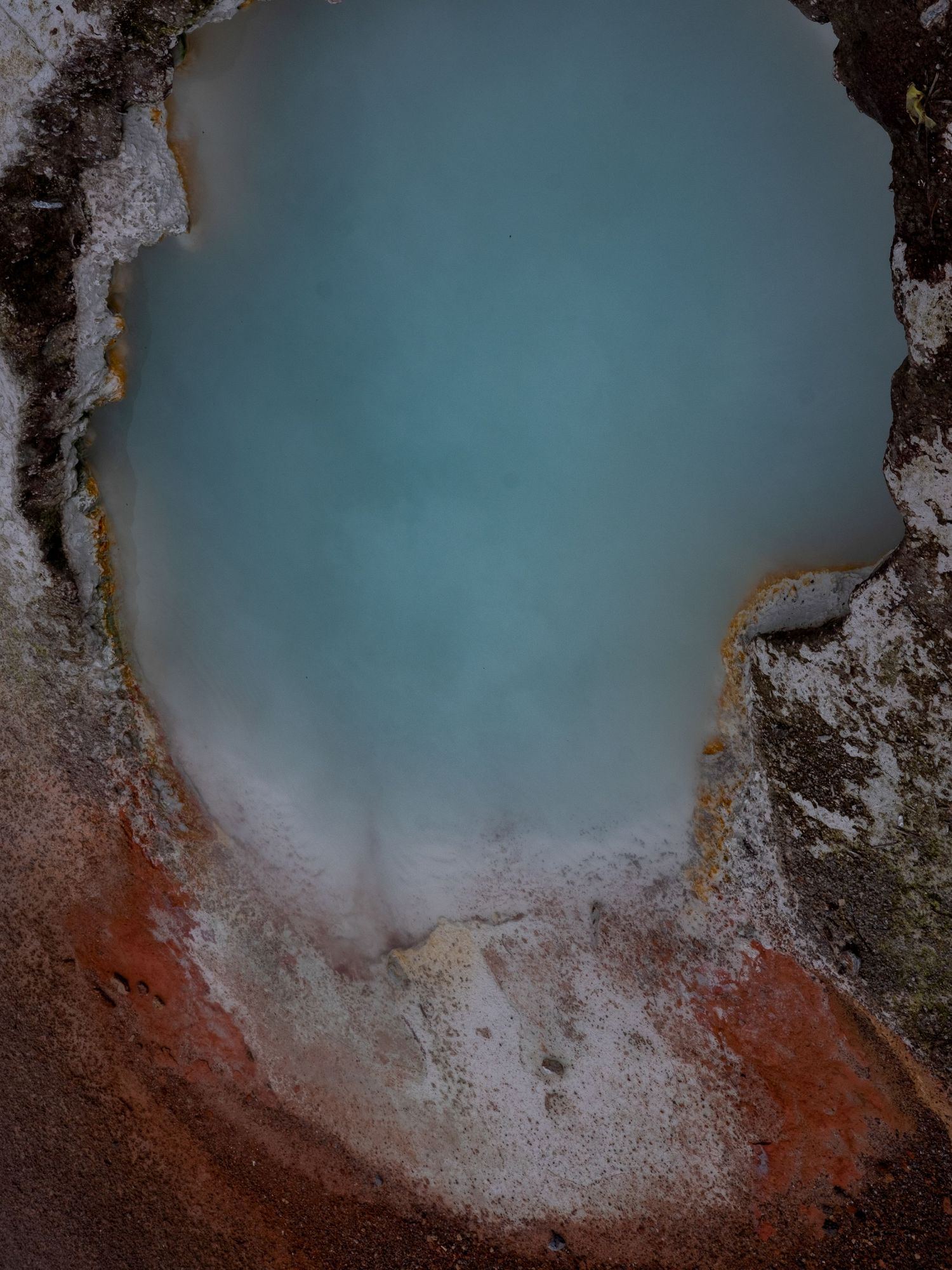 Close-up of a geothermal pool with turquoise water and white mineral deposits.