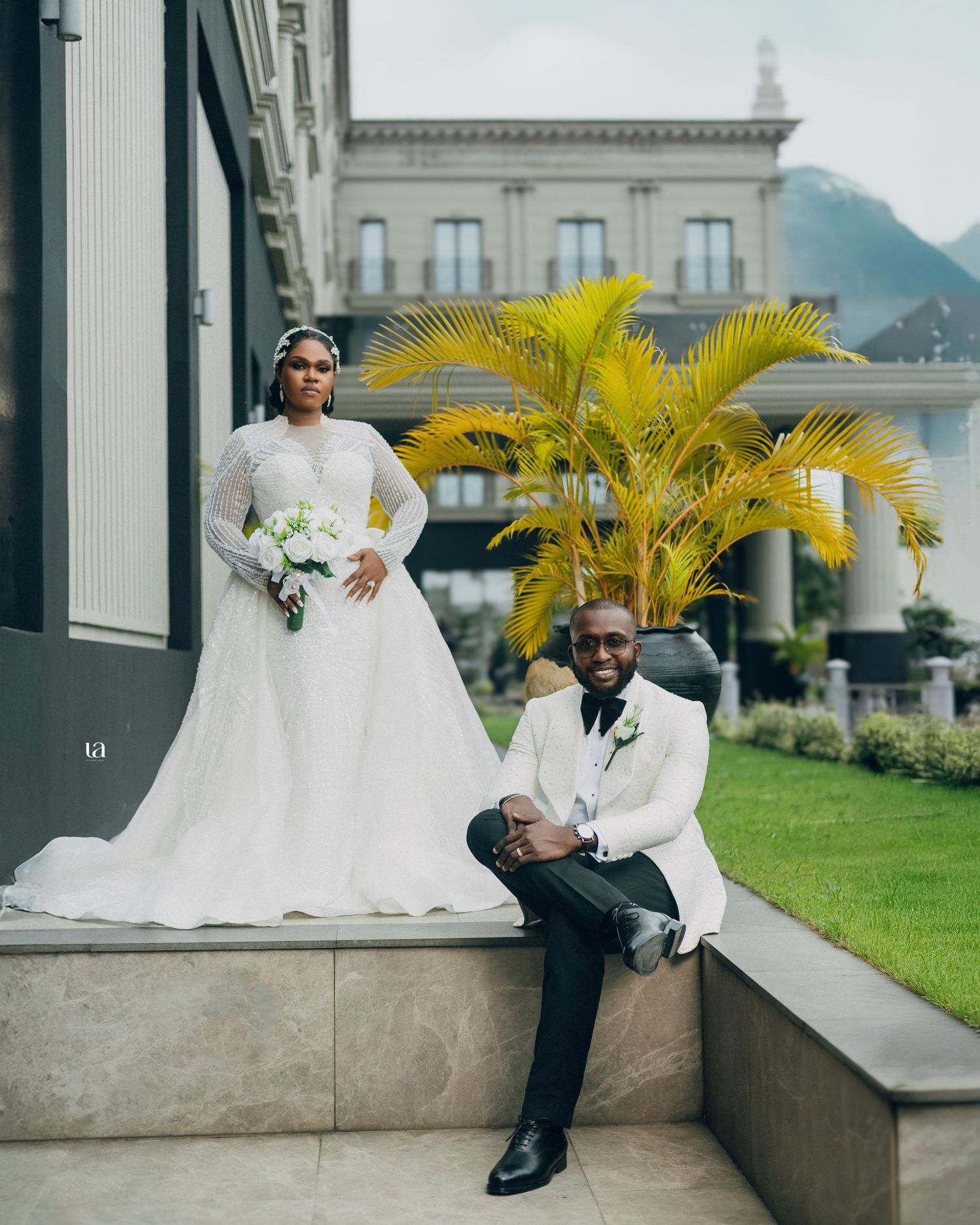 Outdoor wedding portraits on stone steps with tropical palm trees and classical architecture.