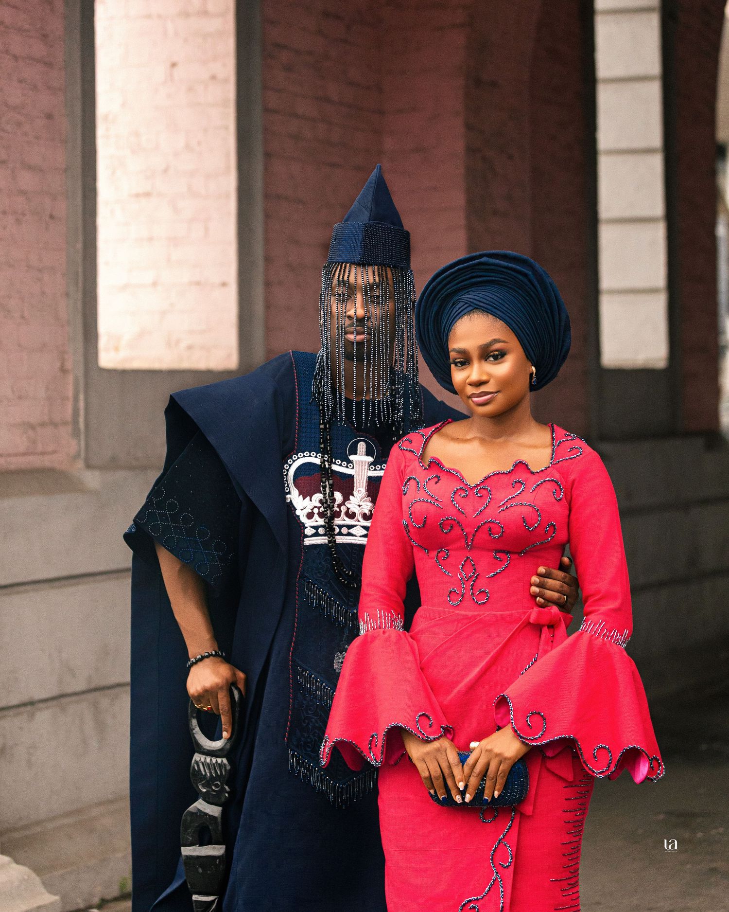 Traditional African fashion shoot featuring red dress and blue headwrap in historic colonnade.