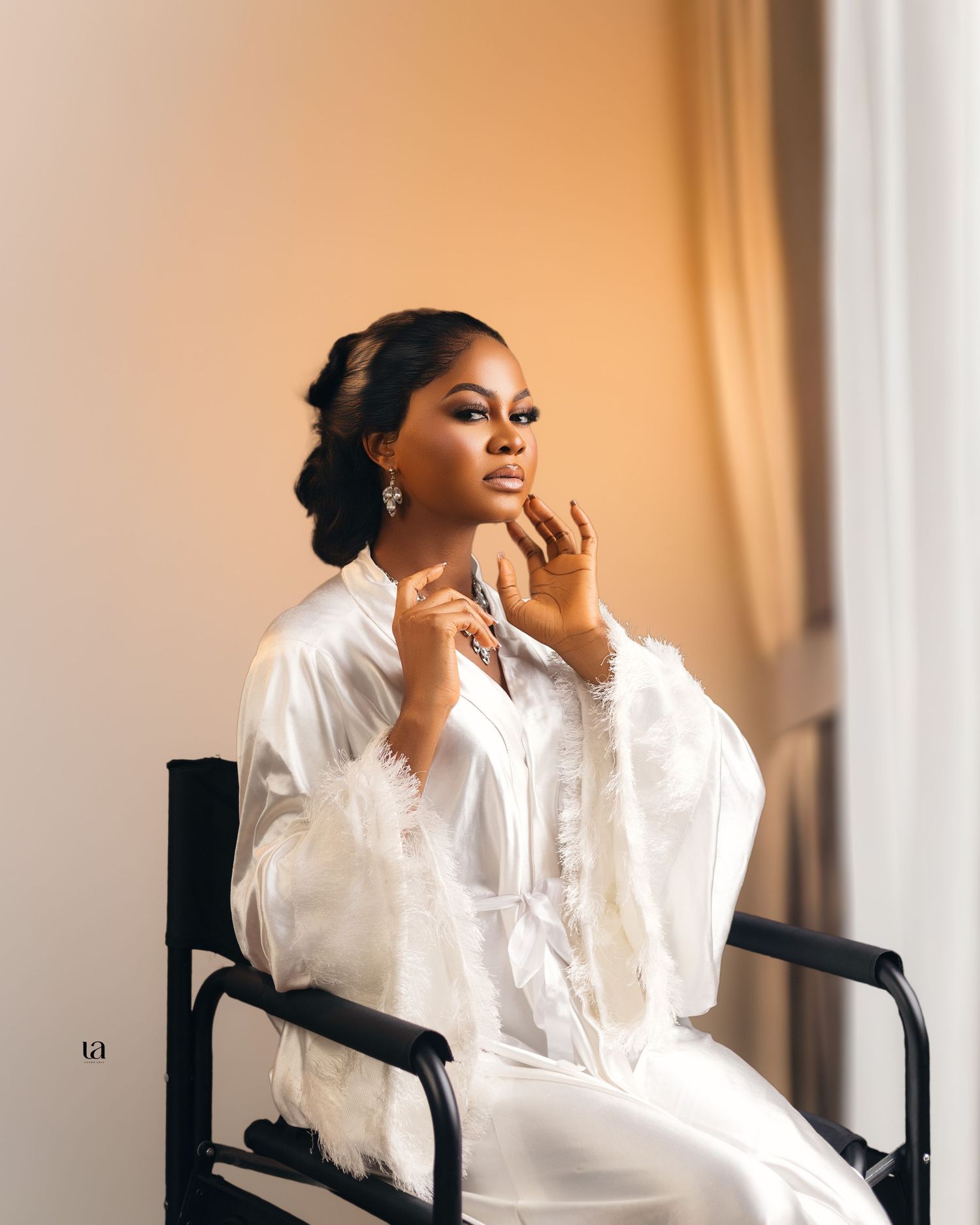Soft portrait series in white flowing blouse seated in director's chair.
