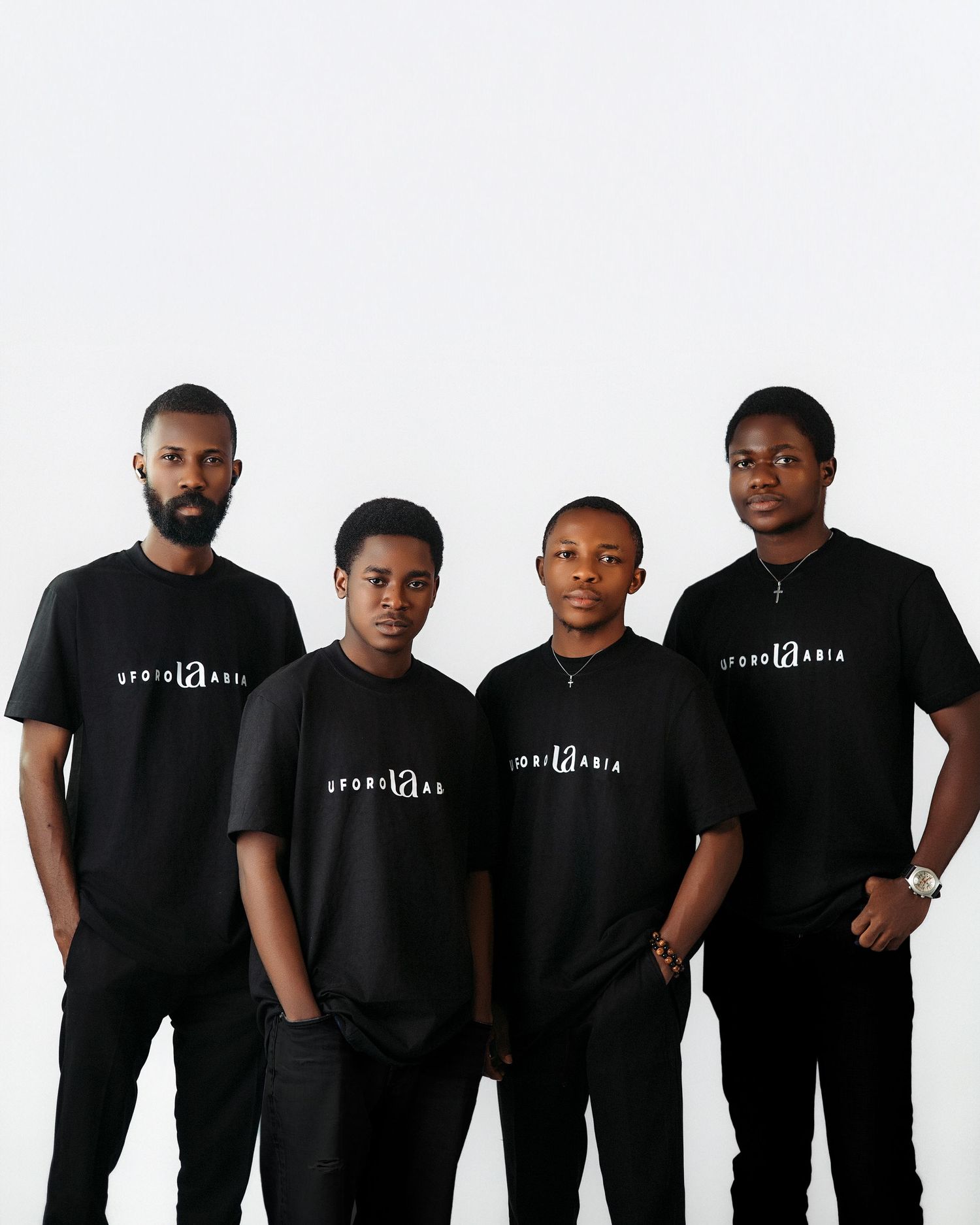 Four men in matching black branded t-shirts pose together against white background.
