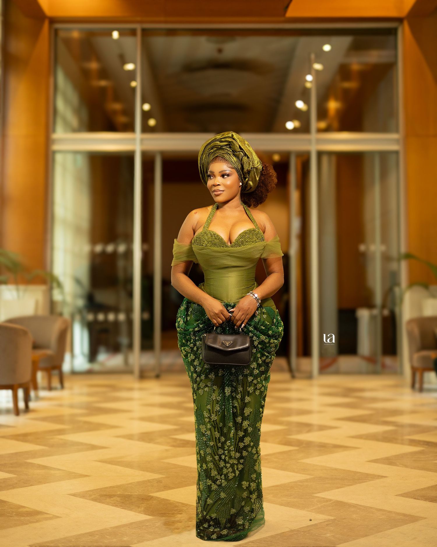 Fashion photography in an indoor venue showing a green patterned dress against warm lighting.